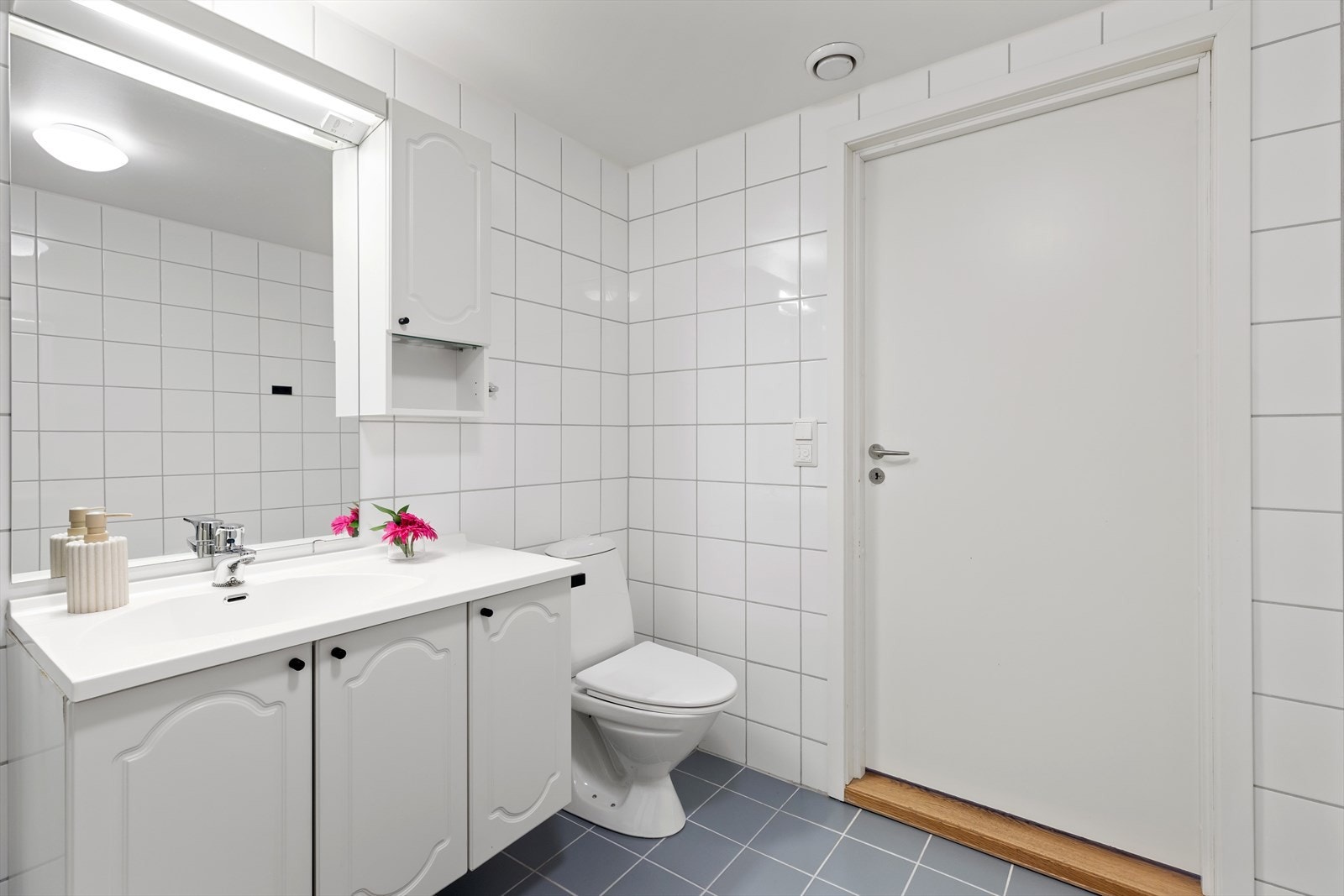 Baderomsinnredningen består av frittstående wc, servant m/underskap, speil m/overlys, veggskap, dusjkarr med inn-/utadslående dusjdører og opplegg for vaskemaskin. Galleribilde