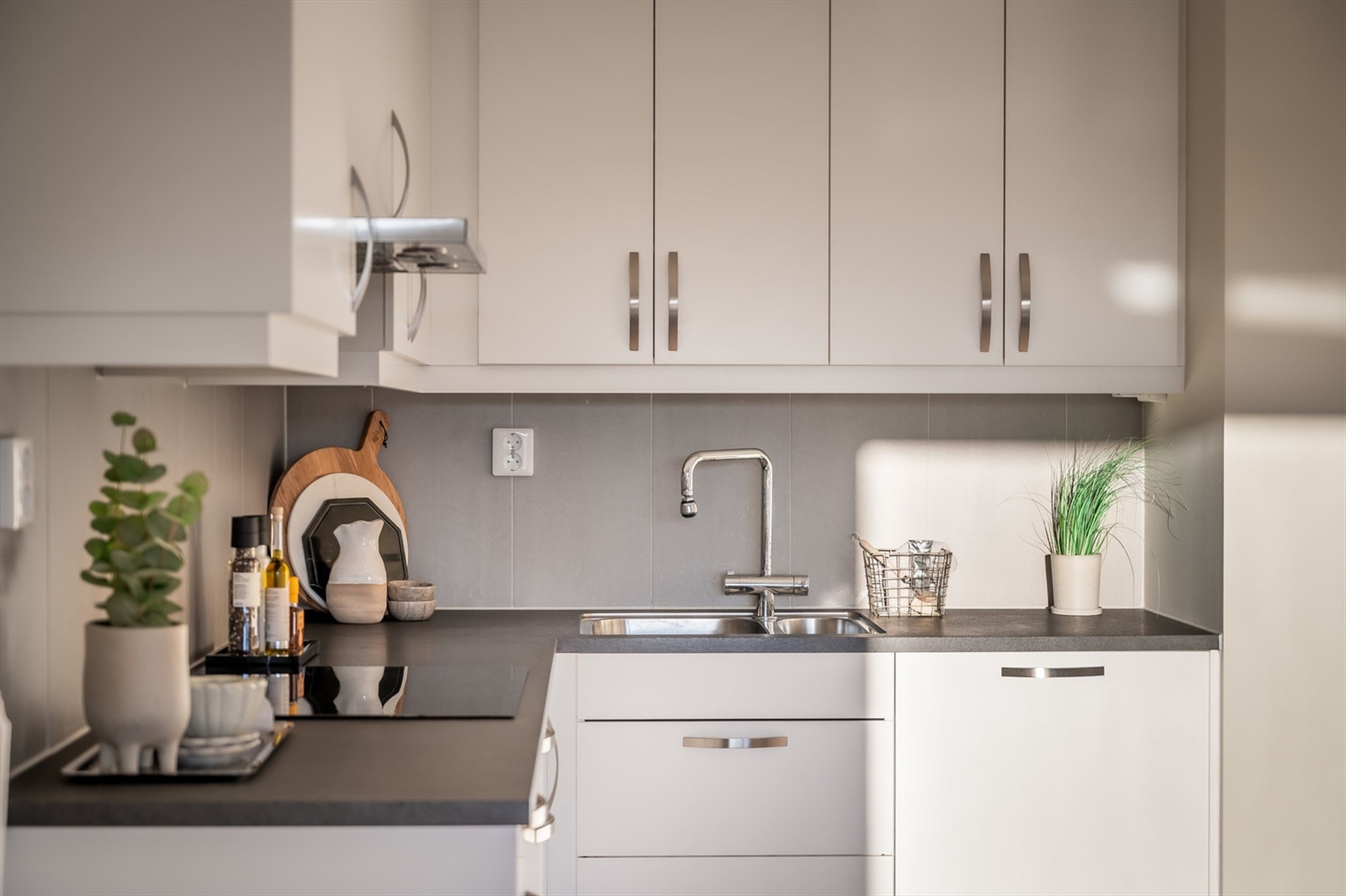 Kjøkkeninnredning med glatte fronter, laminert benkeplate og fliser på vegg over kjøkkenbenk. Galleribilde