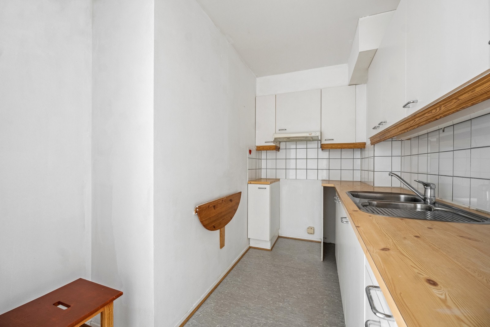 Eldre kjøkkeninnredning med glatte laminerte, skapfronter, laminert benkeplate med fliser på bakvegg, 1 1/2 oppvaskkum med benkebaslag og ventilator. Galleribilde