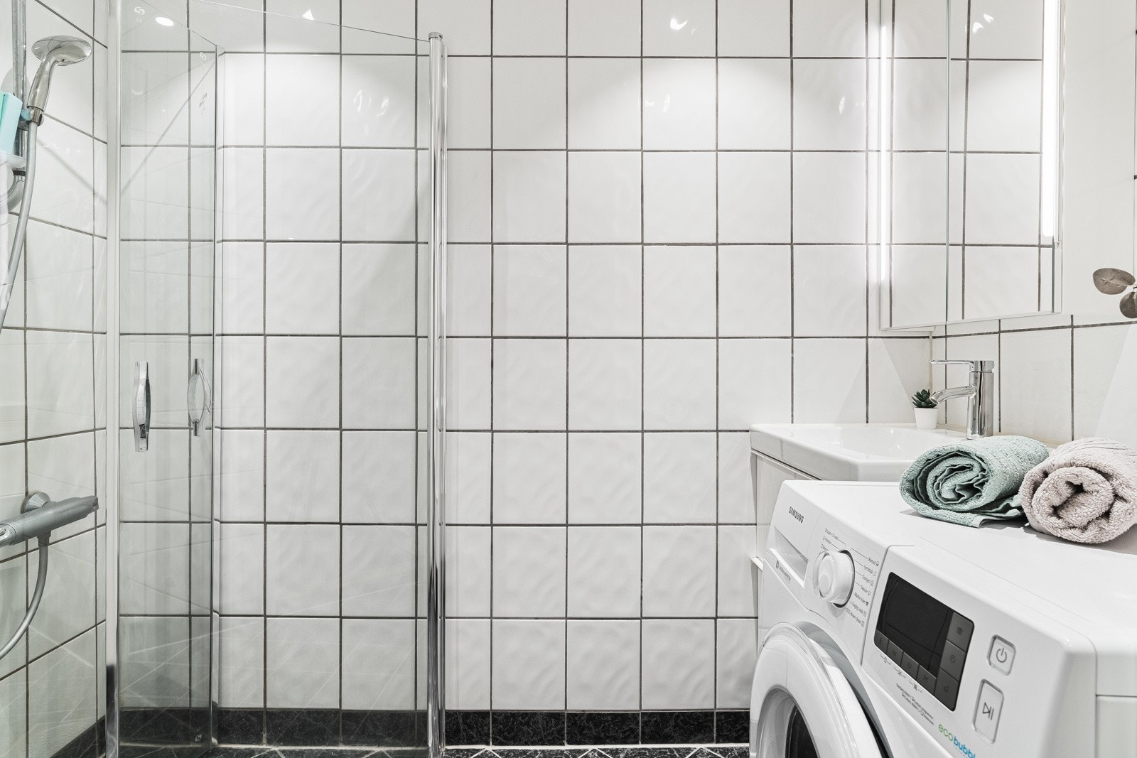 Badet i leiligheten er helfliset med lyse fliser på veggene i kombinasjon med mørke fliser med varmekabler på gulvet. Innfelte downlights i himlingen sikrer rikelig med lys. Galleribilde