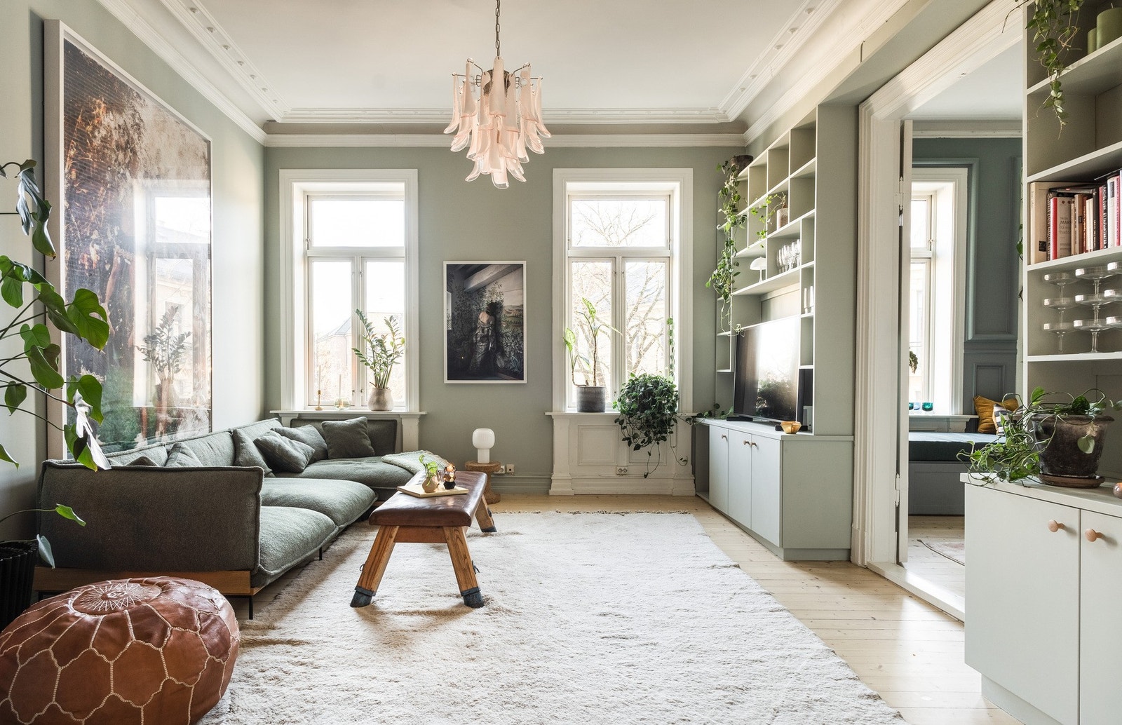 Dagslyset strømmer inn til stuen via store, klassiske bygårdsvinduer. Galleribilde