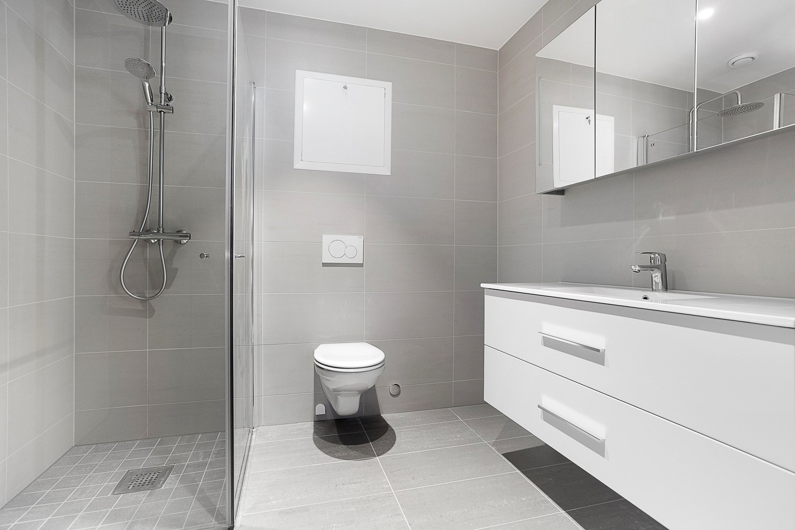 Badet som er i tilknytning til hovedsoverommet er utstyrt med dusjnisje og vegghengt toalett. Det er godt med lagringsplass i speilskap og skuffer under servanten. Galleribilde