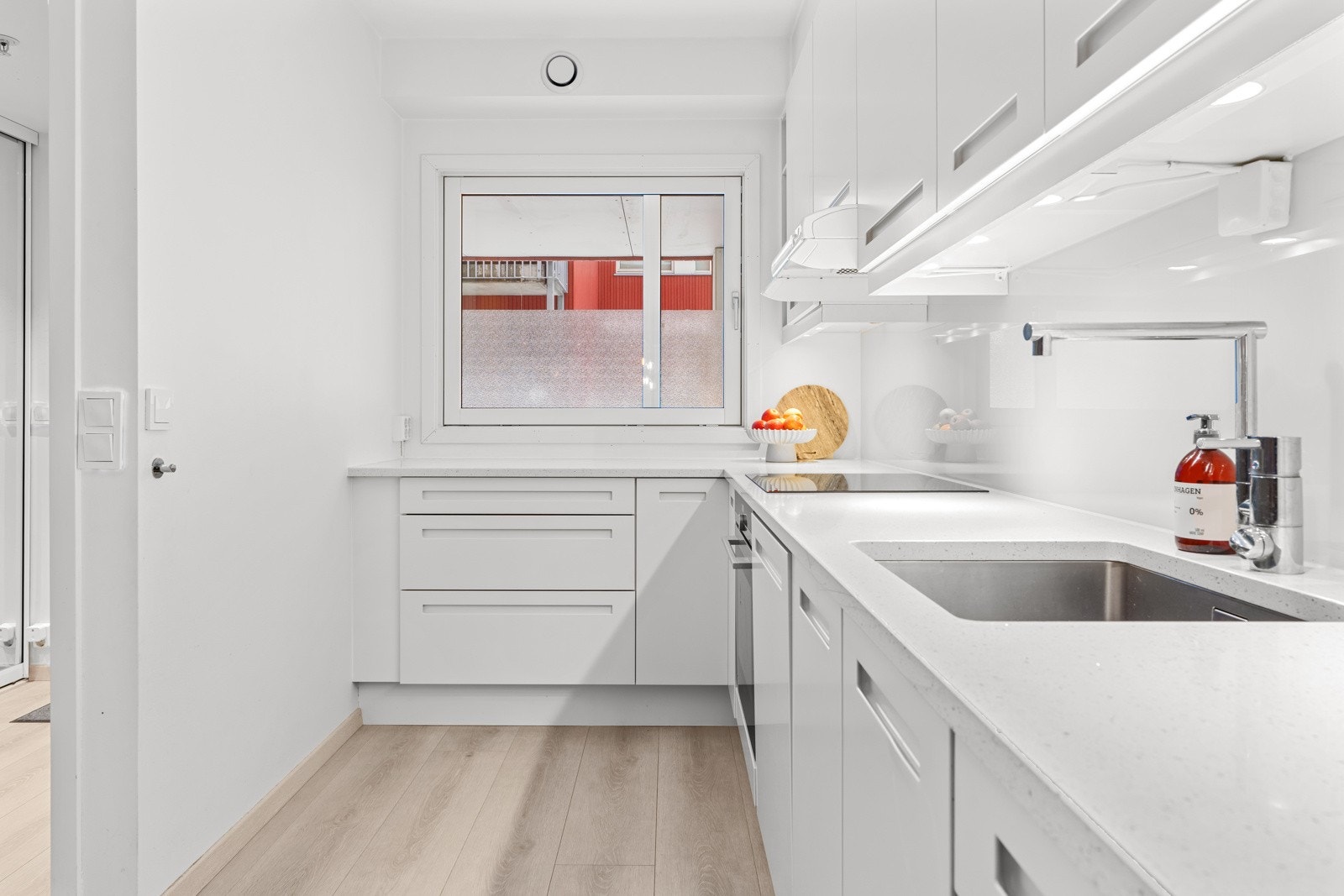 Slette fronter med innfreste håndtak og benkeplate av kompositt. Underlimt oppvaskkum i rustfritt stål med ett-greps armatur. Galleribilde