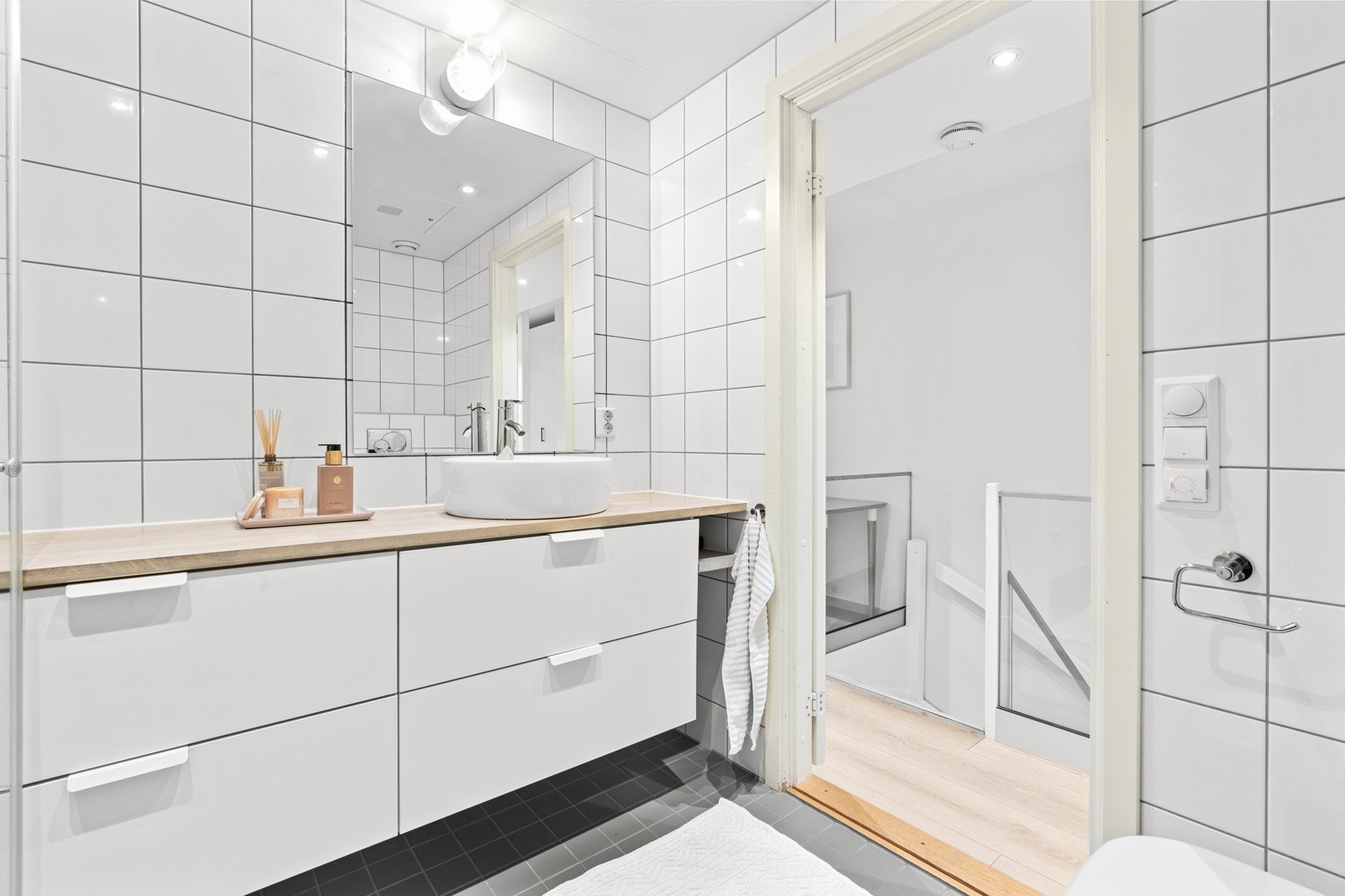 Romslig dusjhjørne med innfellbare rette dusjvegger og vegghengt toalett med skjult sisterne. Galleribilde