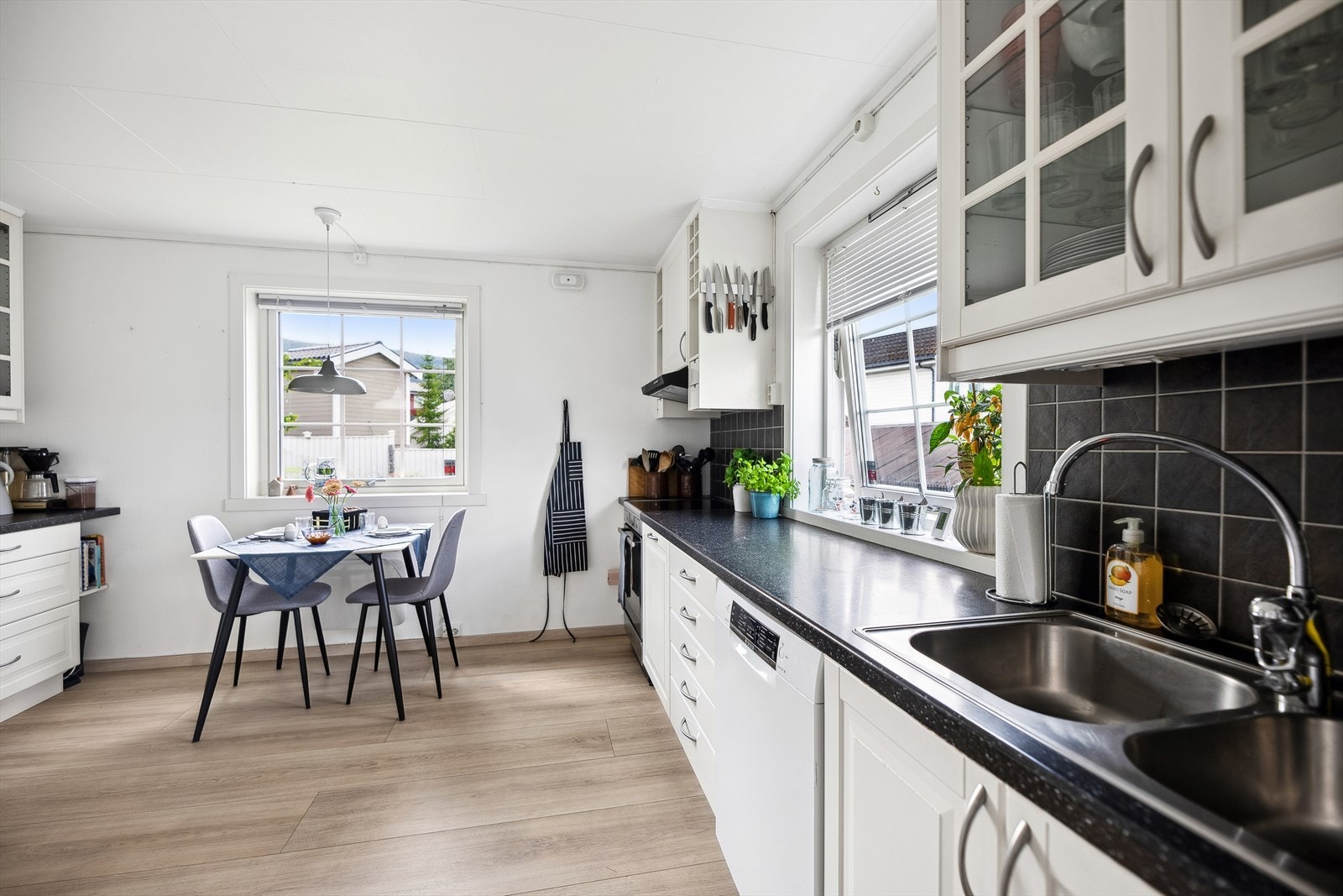 Kjøkkeninnredning med laminerte slette og profilerte fronter, noen overskap med glassdører og laminert benkeplate med nedfelt oppvaskkum Galleribilde