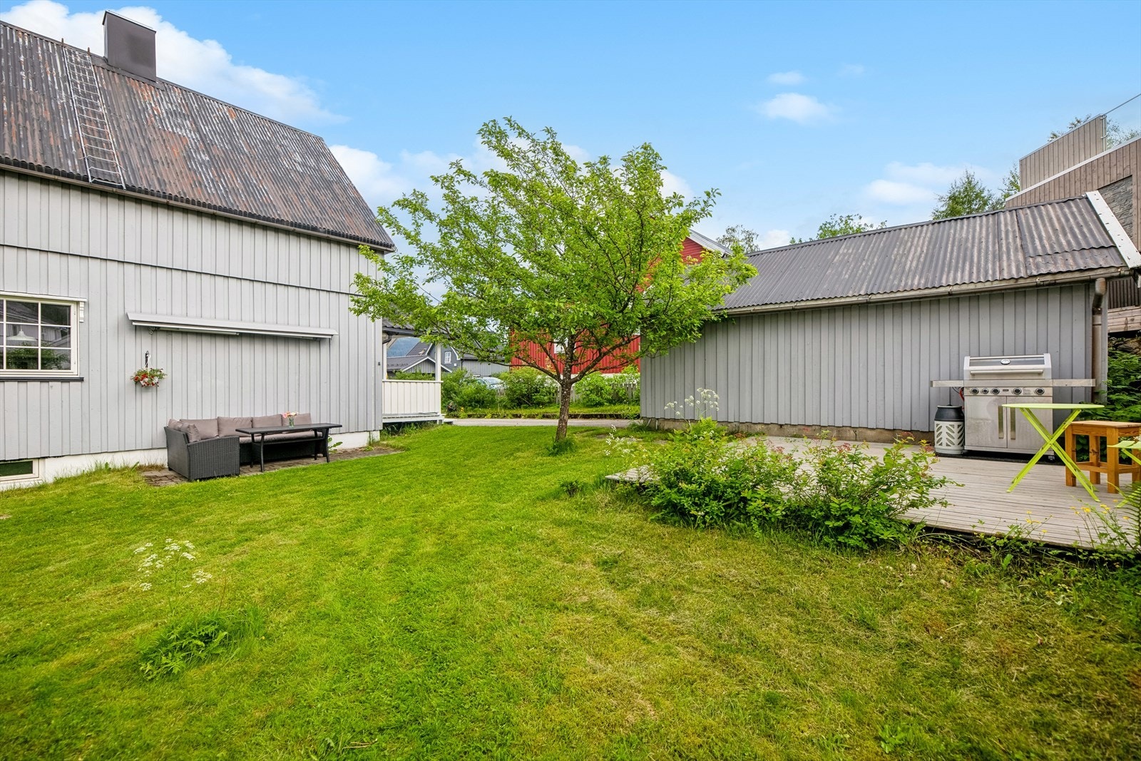 Tomten er pent opparbeidet med plen og annen beplantning. Galleribilde