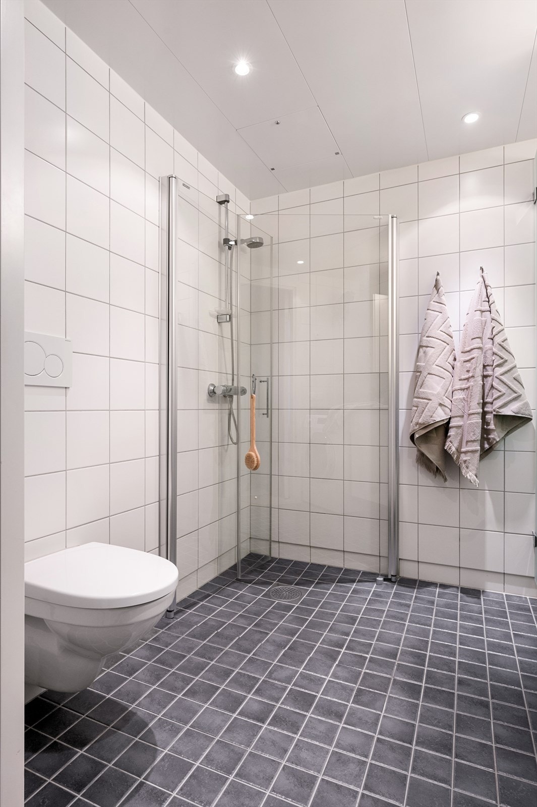 Badet er utstyrt med dusjhjørne med innfellbare glassdører og vegghengt toalett Galleribilde