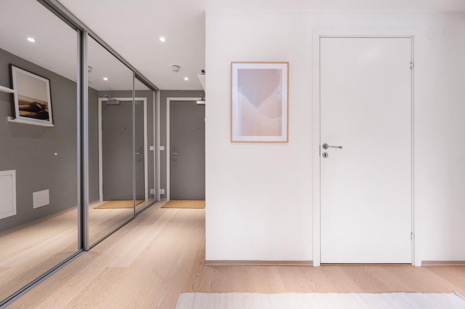 Lys og innbydende entré med lekker eikeparkett på gulv og downlights i himling som gir et god førsteinntrykk av boligen Galleribilde