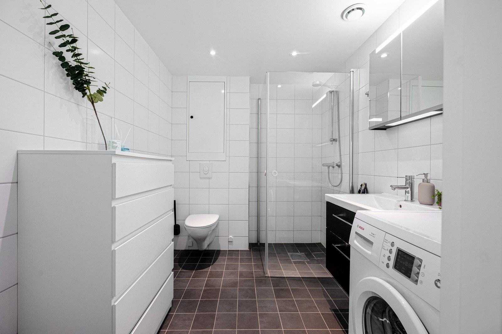 Badet har dusjhjørne med glassdører og vegghengt toalett. Galleribilde