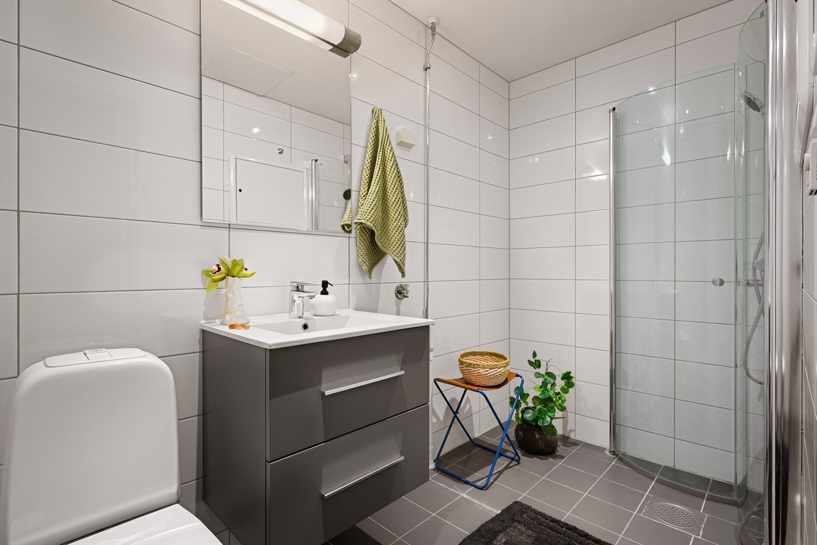 Det arealsmarte badet har tidløse lyse fliser på vegger og mørke på gulv. Her har du også varmekabler i gulv, som holder føttene varme. Galleribilde