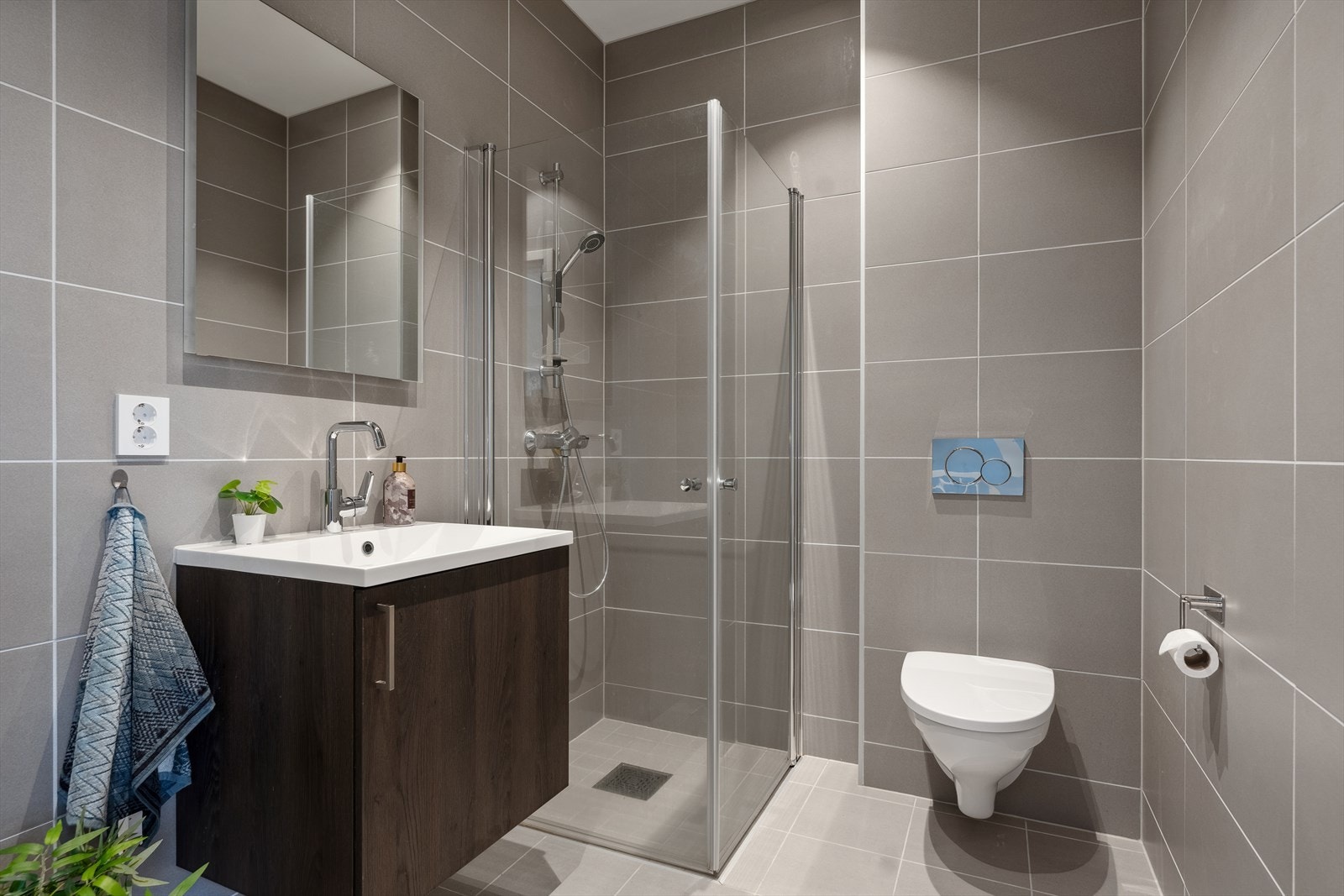 Innbydende helfliset bad med varme i gulv. Rommet har vegghengt toalett, dusj, servant og servantskap. Balansert ventilasjon med avtrekksventil og luftespalte under dør. Et godt sted å starte dagen! Galleribilde