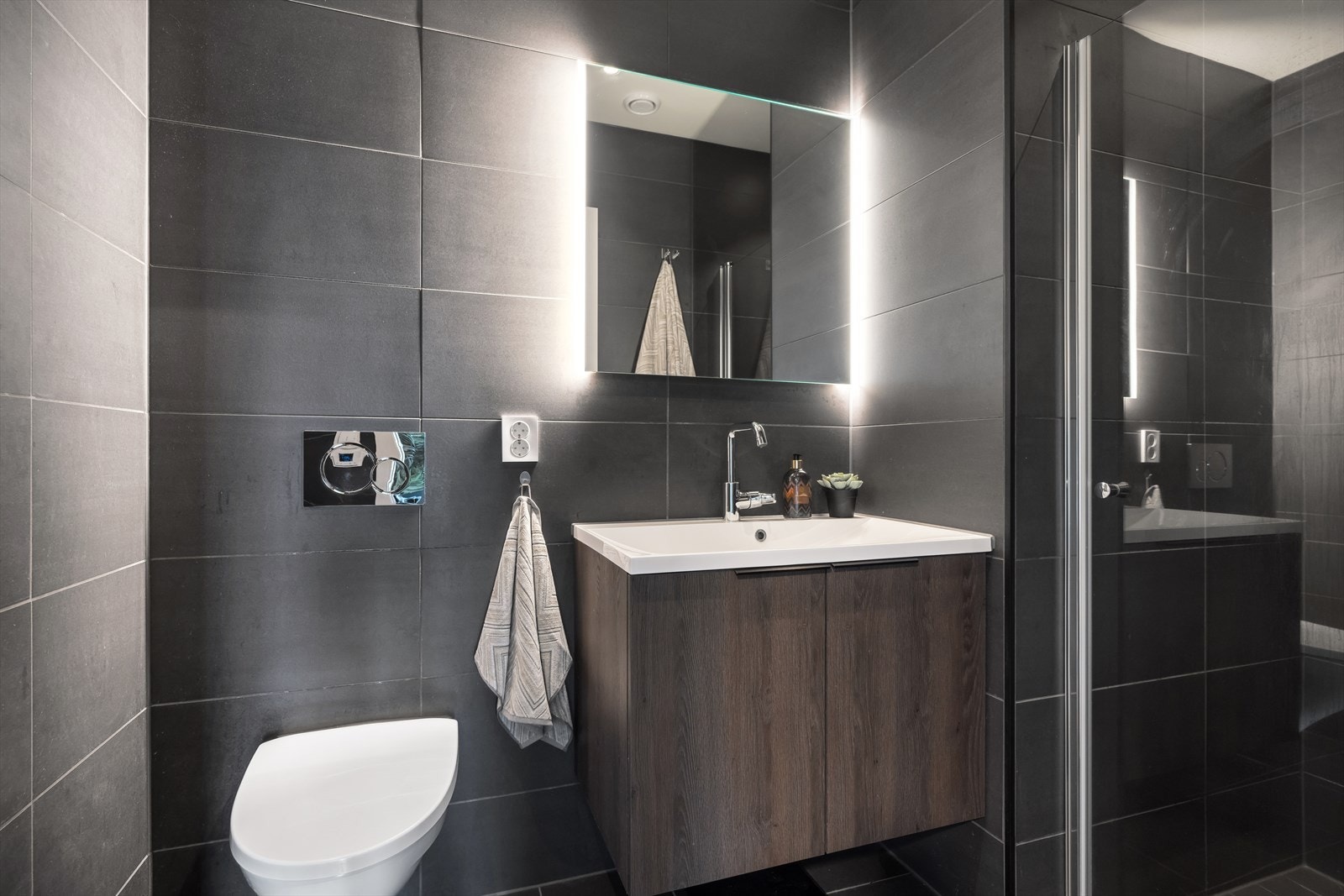 I tilknytning til hovedsoverommet ligger ett lekkert helfliset bad med varme i gulv. Rommet har vegghengt toalett, servant og dusj. Servantskap. Balansert ventilasjon med avtrekksventil og luftespalte under dør. Galleribilde