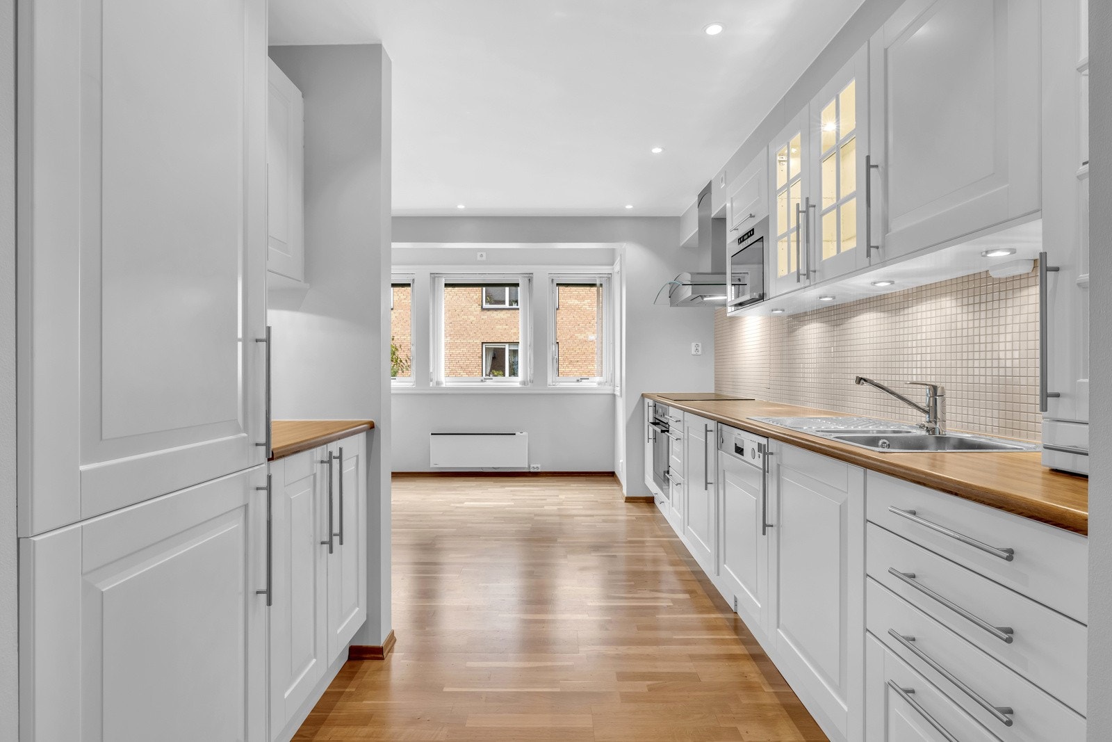 Kjøkkeninnredningen har hvitmalte profilerte fronter, benkeplater av laminat, nedsenket oppvaskkum med ettgreps armatur. Galleribilde