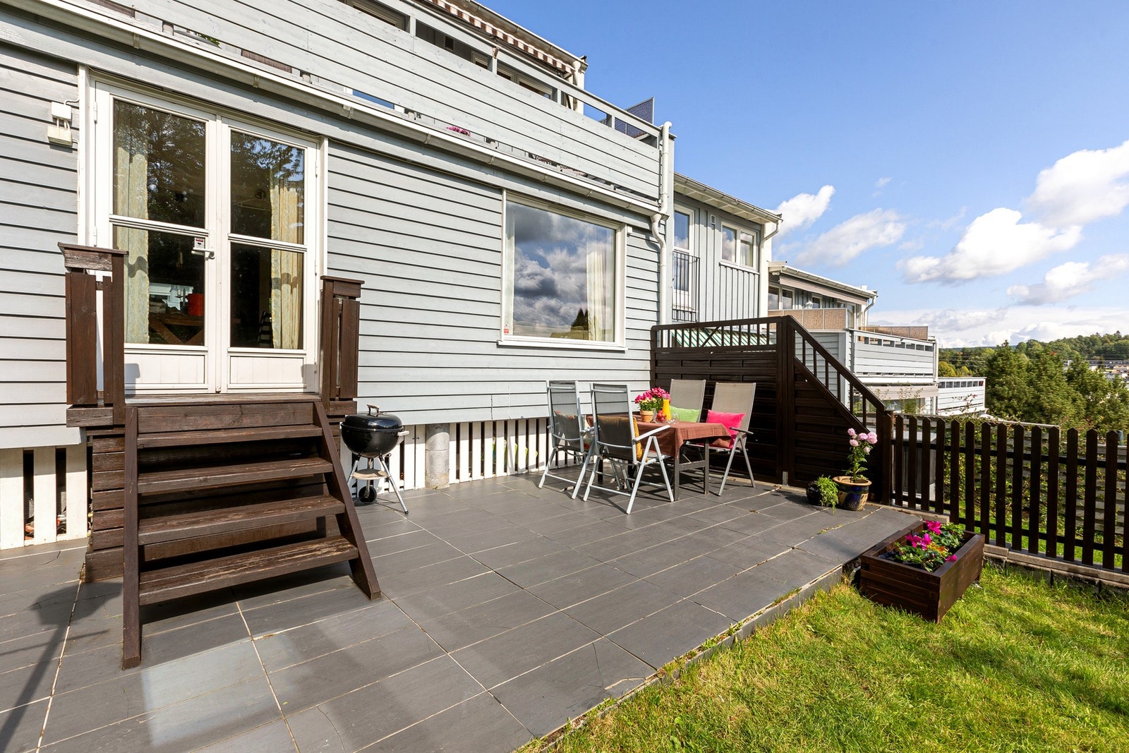 En solrik terrasseplatting med fliser, skjermet fra nabo med levegg. Galleribilde