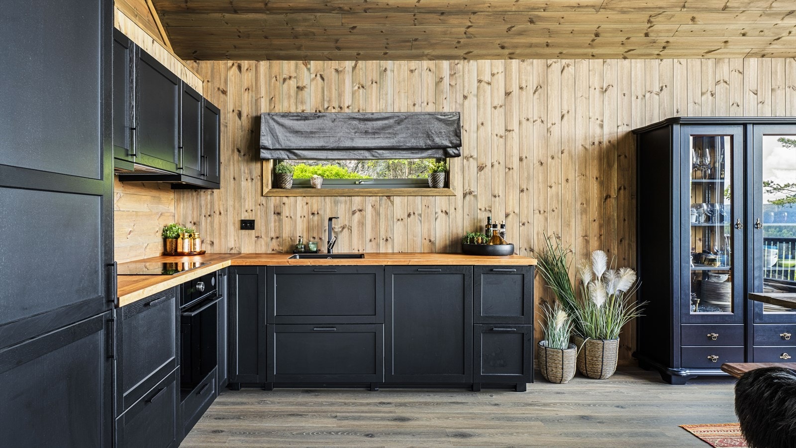 Hytta har en god og lun atmosfære med beiset panel og mørke detaljer Galleribilde