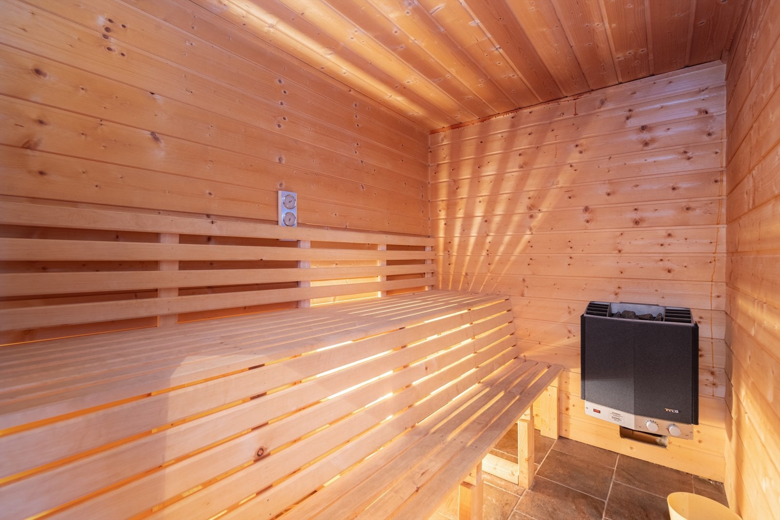 Tilliggende baderommet er det en deilig badstue med plassbygde badstuebenker i to nivåer. Flis på gulv, og panel på øvrige overflater. Veggmontert elektrisk badstueovn. Galleribilde