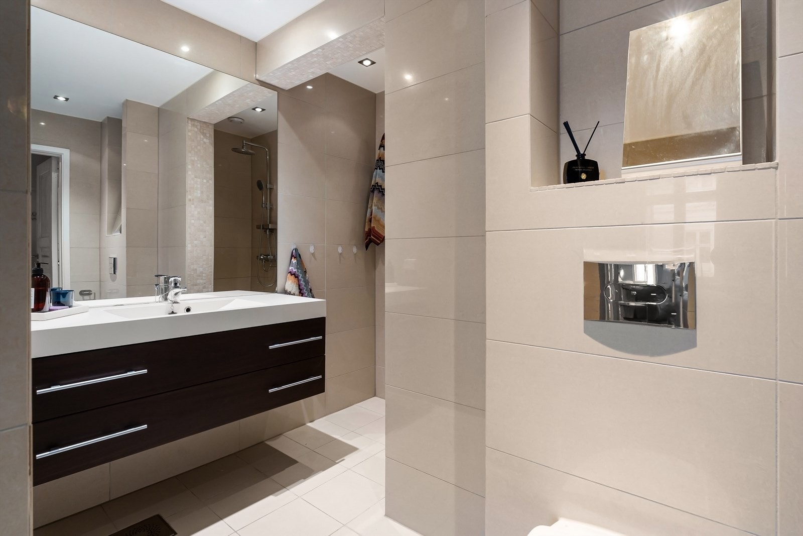 Flislagt bad fra 2010 med stort benkeskap og vegghengt toalett Galleribilde