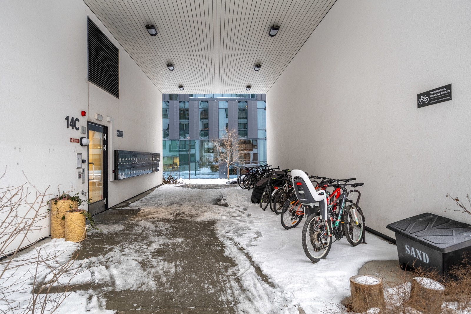 Inngangsparti med postkassestativ og sykkelparkering. Det er større sykkelbod tilgjengelig innendørs i borettslagets fellesarealer. Galleribilde