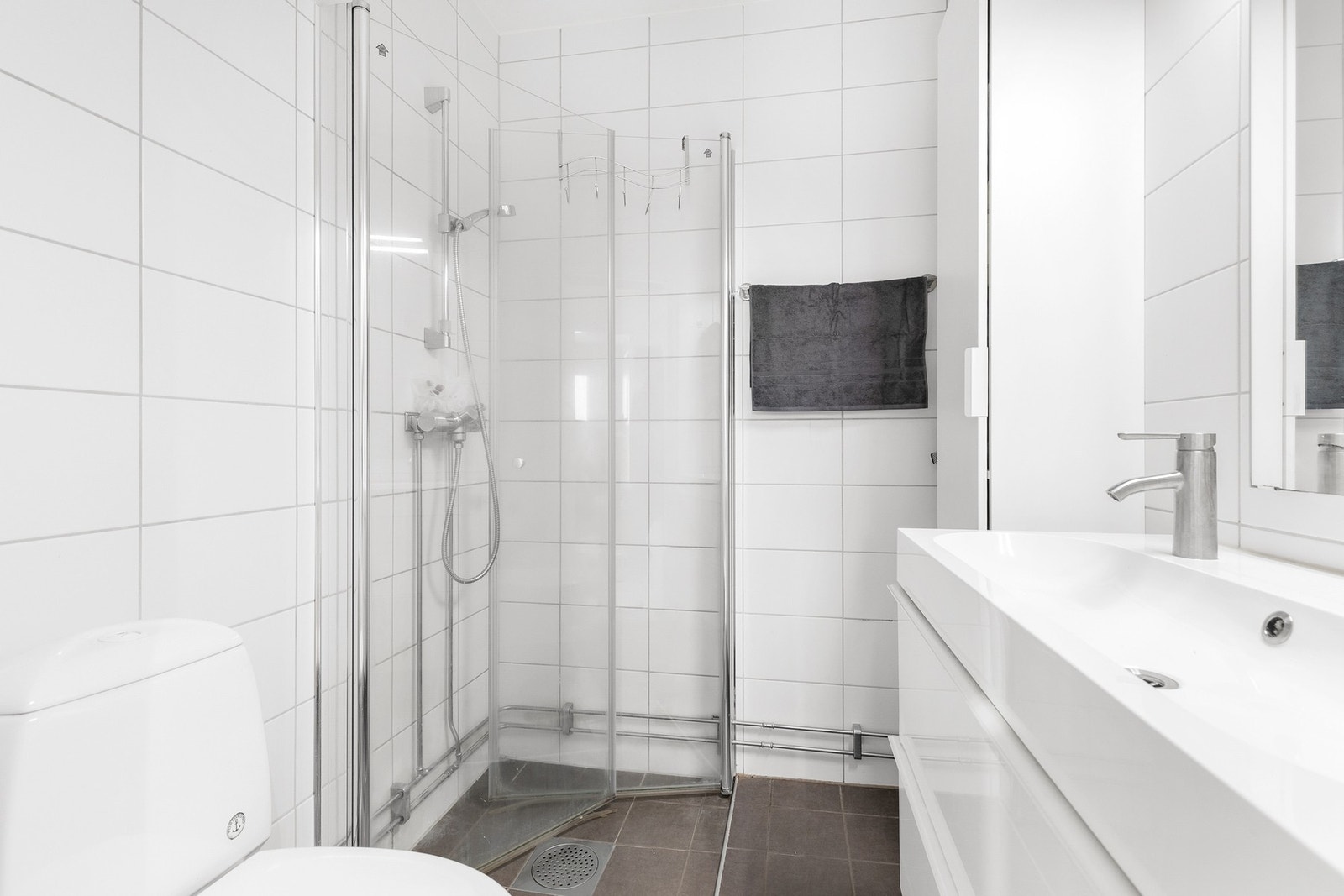 Badet er utstyrt med gulvstående toalett og dusjhjørne med innadslående vegger Galleribilde