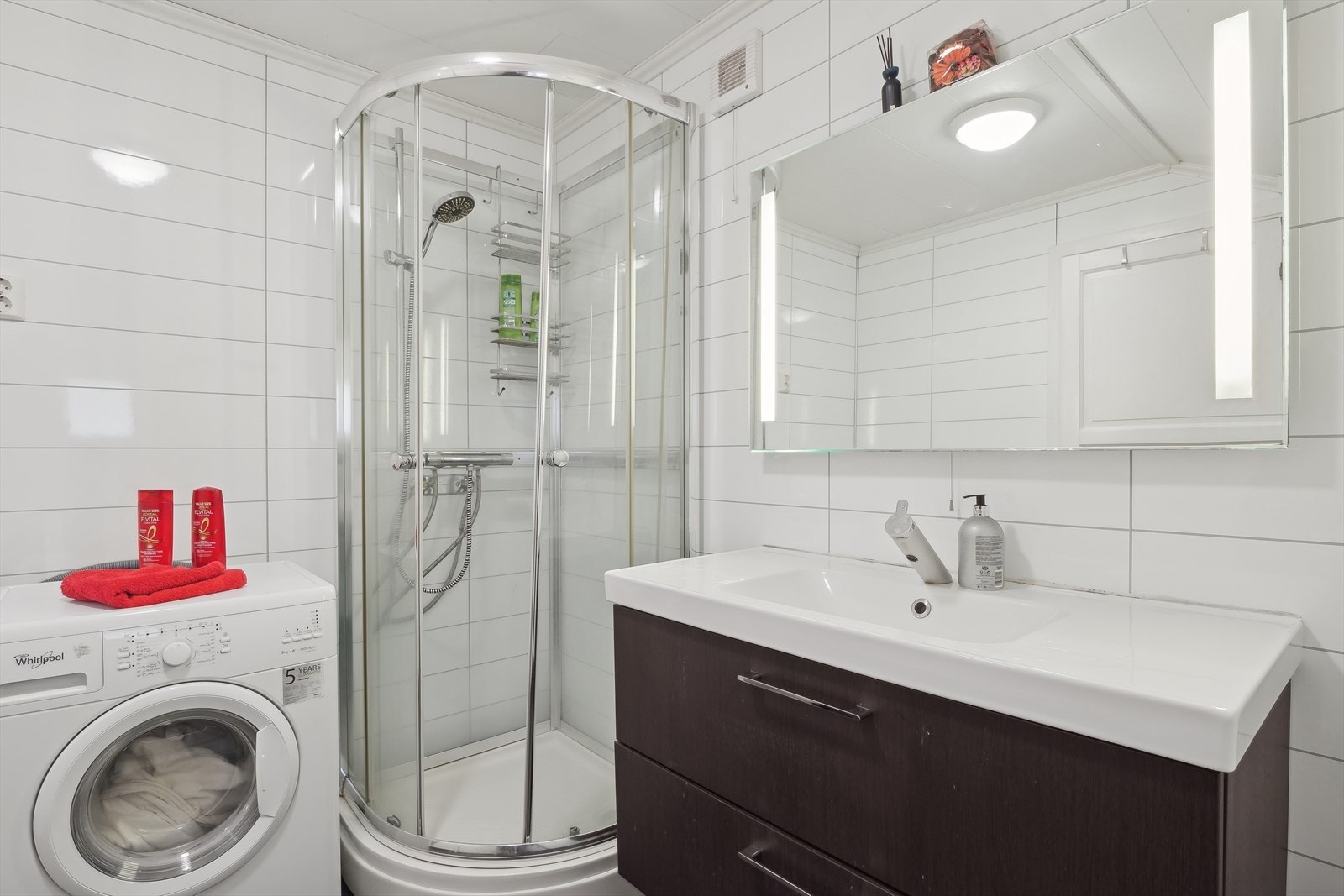 Baderom utstyrt med baderomsinnredning, toalett, dusj og opplegg for vaskemaskin Galleribilde