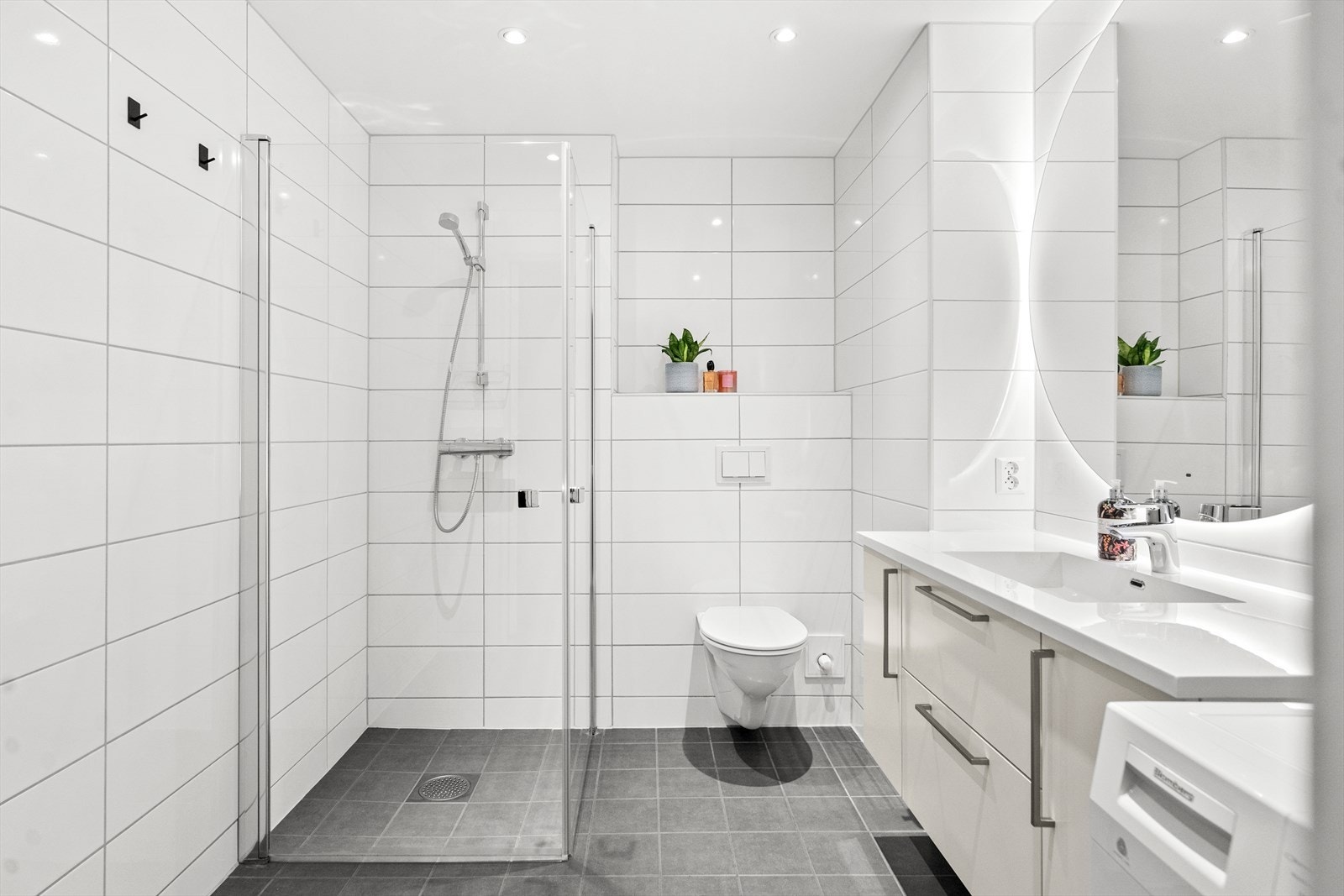 Badet er delikat innredet med grå gulvfliser, hvite veggfliser, gulvvarme og downlights. Galleribilde