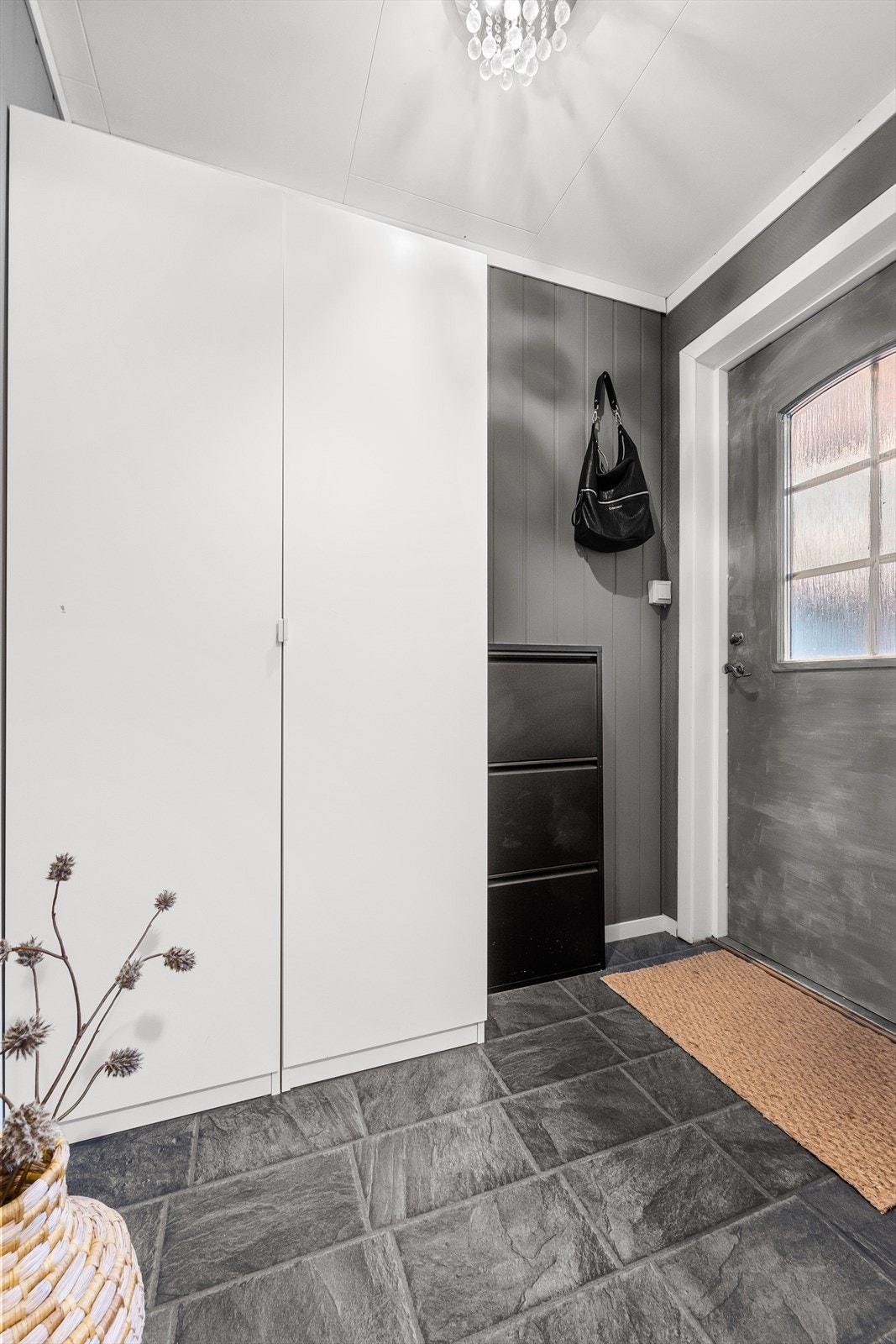 Inngang via lys entré med flislagt gulv. Her har du plass til å henge fra deg yttertøy og sko i garderobeskap og på oppheng. Galleribilde