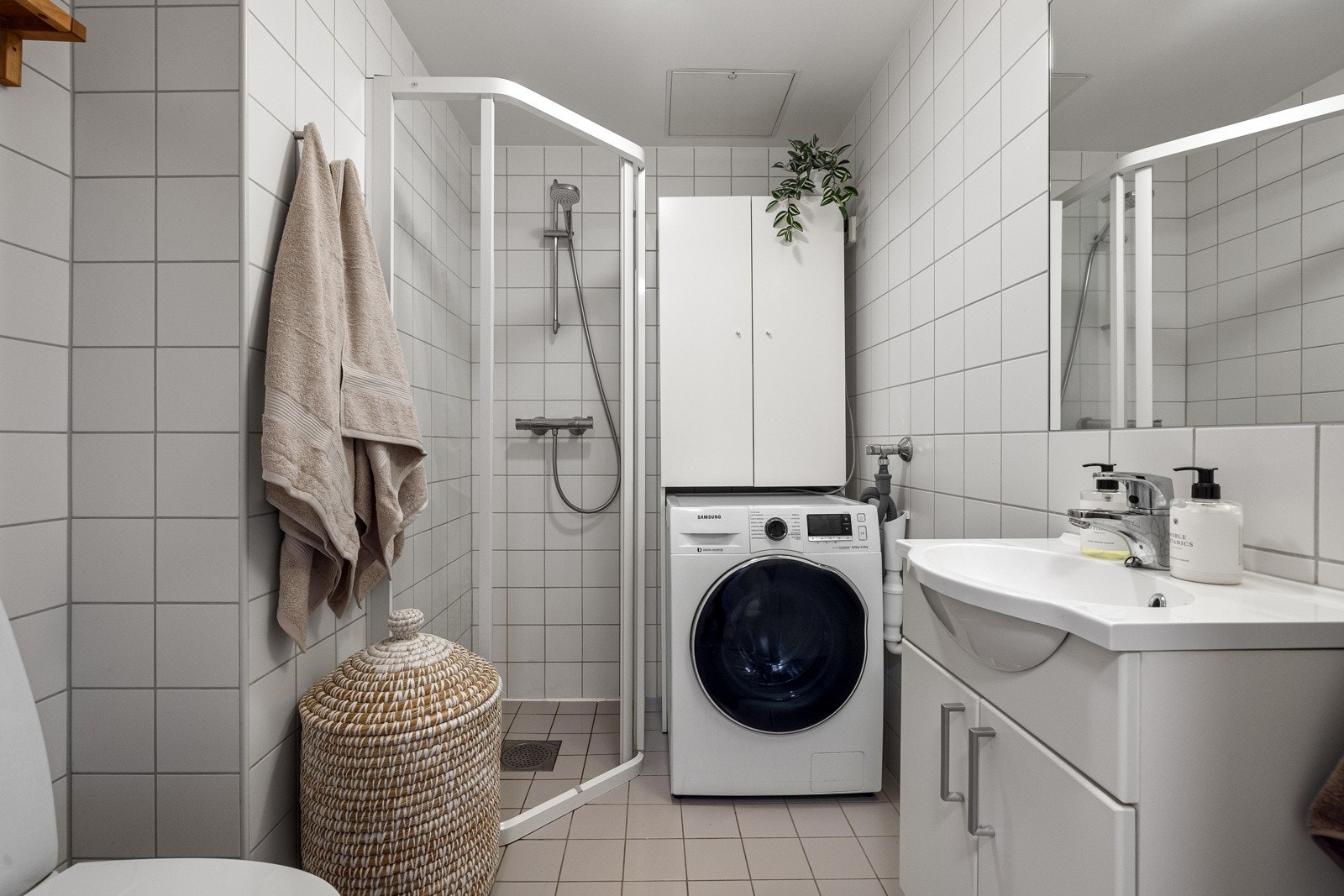 Flott bad med flis på vegg og gulv, malte plater i taket. Rommet er innredet med dusjhjørne, toalett, servant i innredning og opplegg for vaskemaskin. Galleribilde