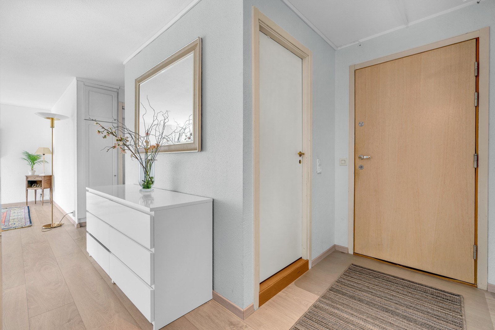 Entréen har hvitmalte overflater og lyst laminat på gulv. Galleribilde