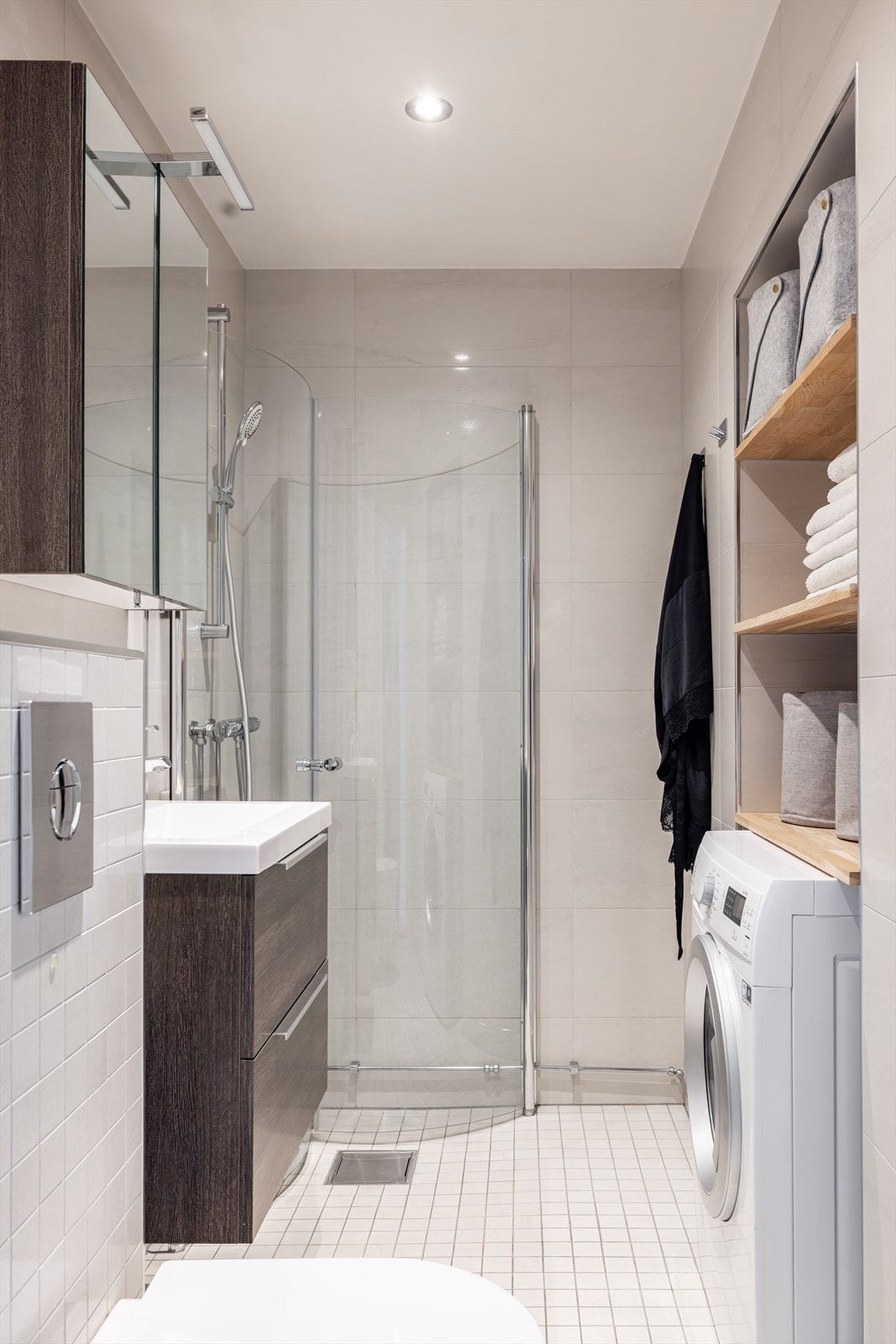 Badet har smarte lagringsmuligheter og opplegg for vaskemaskin. Praktiske hyller over vaskemaskinen. Galleribilde