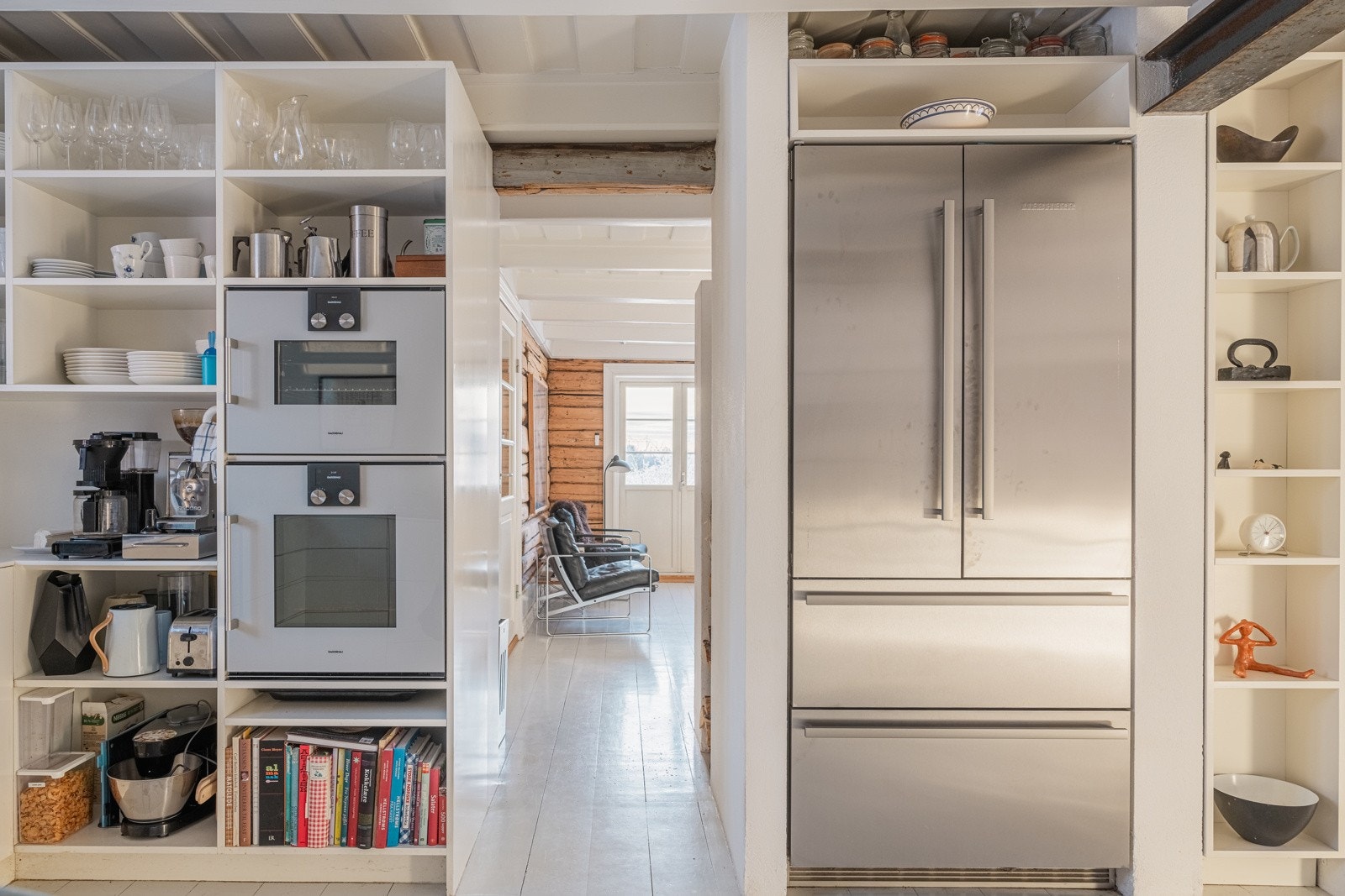 Innredning med glatte fronter og benkeplate av corian. Plater på vegg over benkeplaten og belysning under ventilator. Kjøkkenet har opplegg for platetopp, oppvaskmaskin, stekeovn, dampovn og komi kjøl/frys. Galleribilde