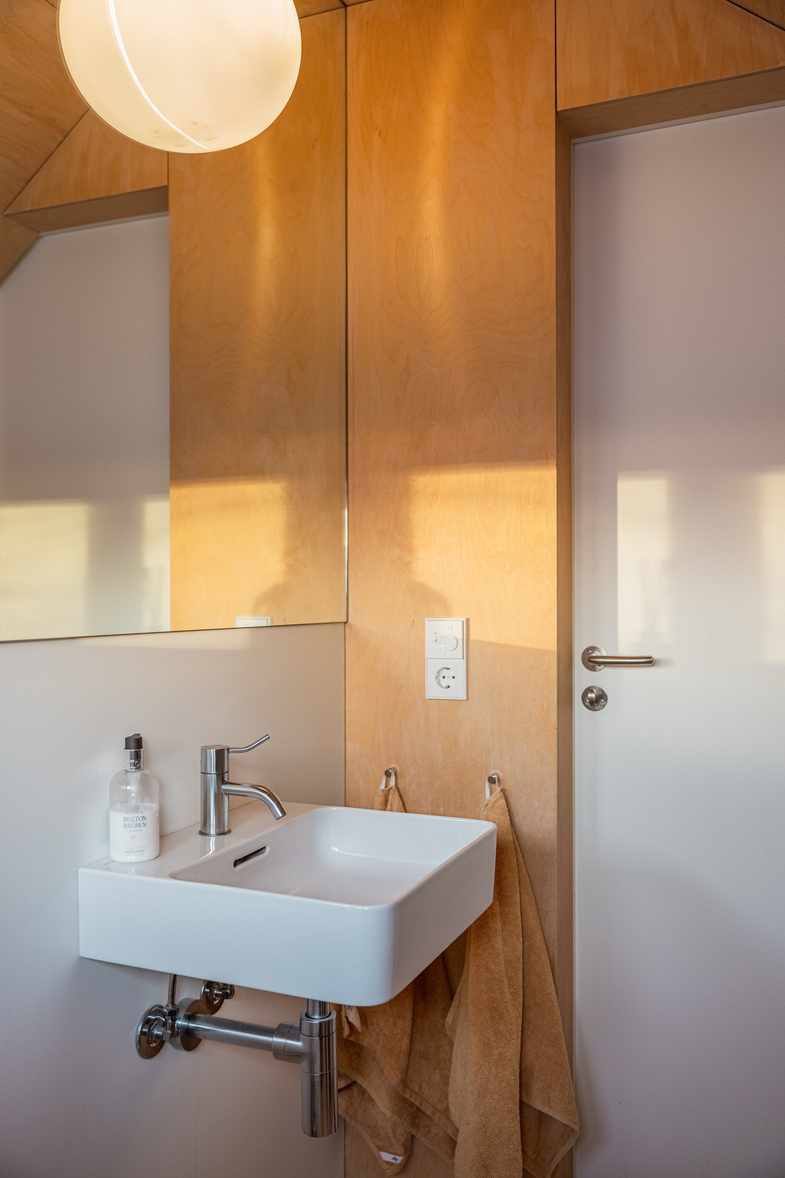 Toalettrommet er utstyrt med et vegghengt toalett og en fritthengende servant Stort, pålimt speil på vegg over servant. Veggmontert toalett. Belysning via lampe i himling. Galleribilde