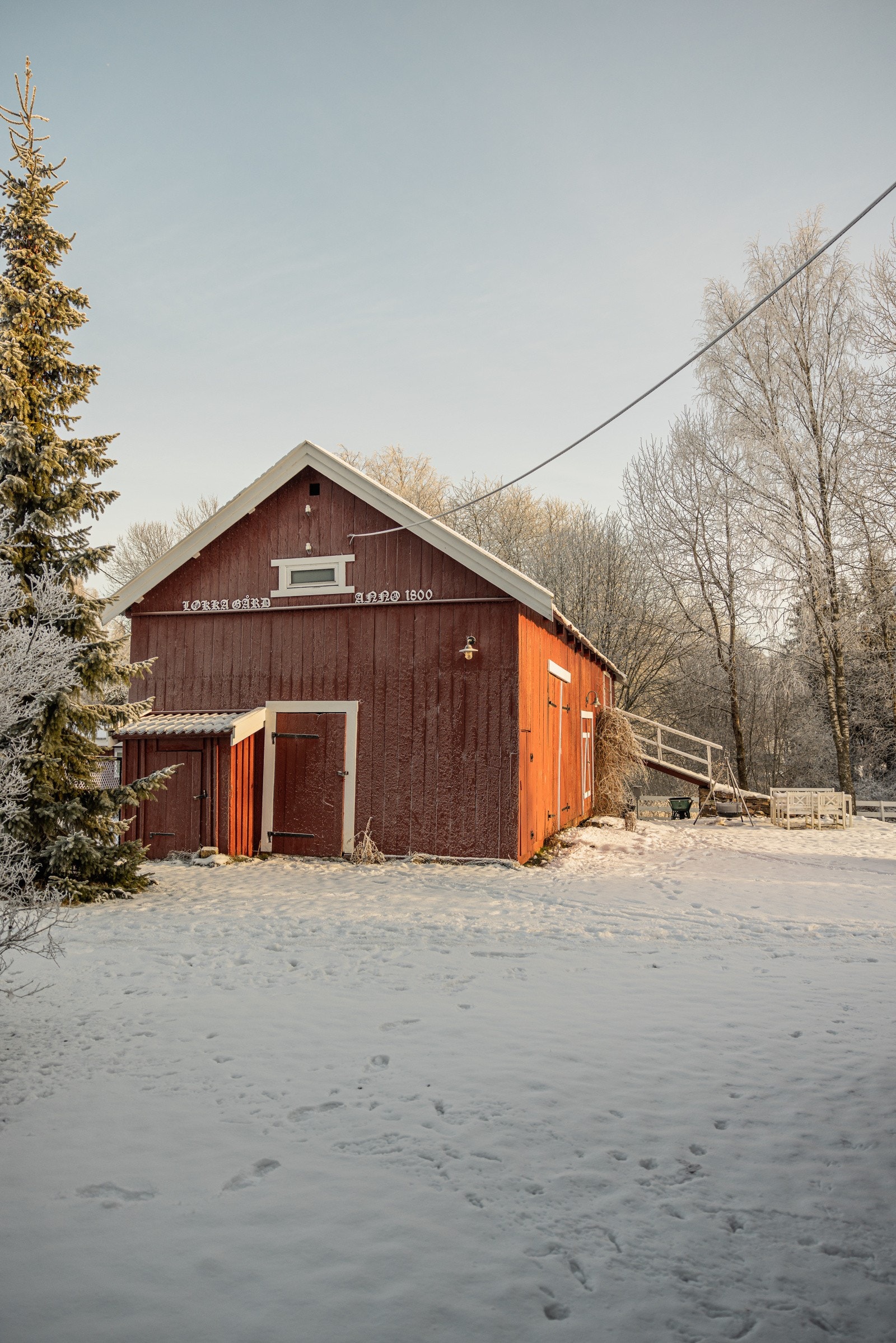 Låven er en eldre, tradisjonell konstruksjon med en rektangulær form, rødmalt treverk og hvite detaljer. Galleribilde