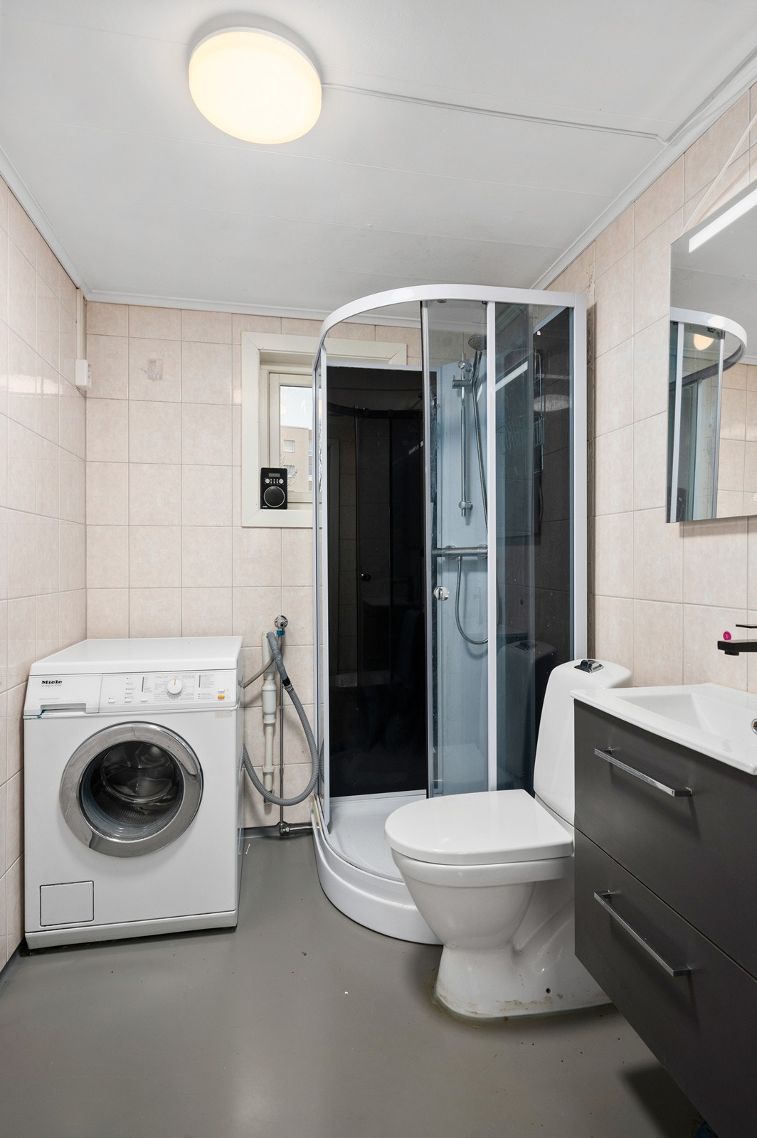 Baderommet er innredet med dusjkabinett, servant med skap, toalett og opplegg for vaskemaskin. Galleribilde