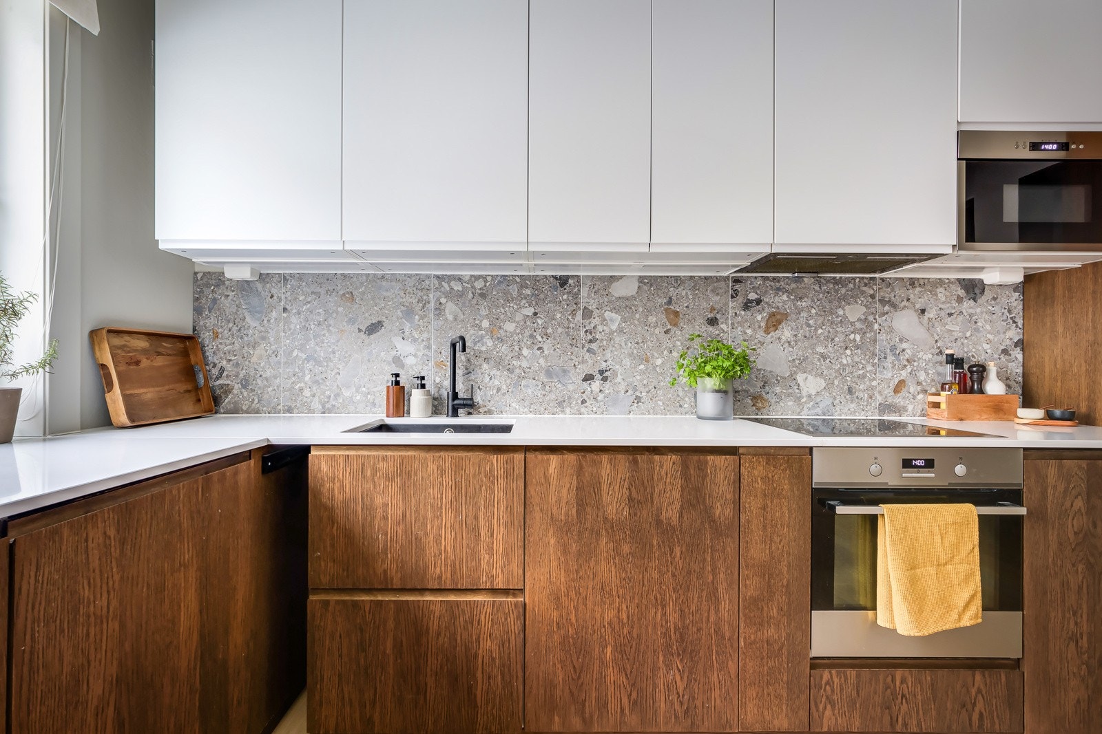 Innredningen har glatte fronter av mørkt tre i kombinasjon med lys og delikat kompositt benkeplate med nedfelt oppvaskkum. Galleribilde