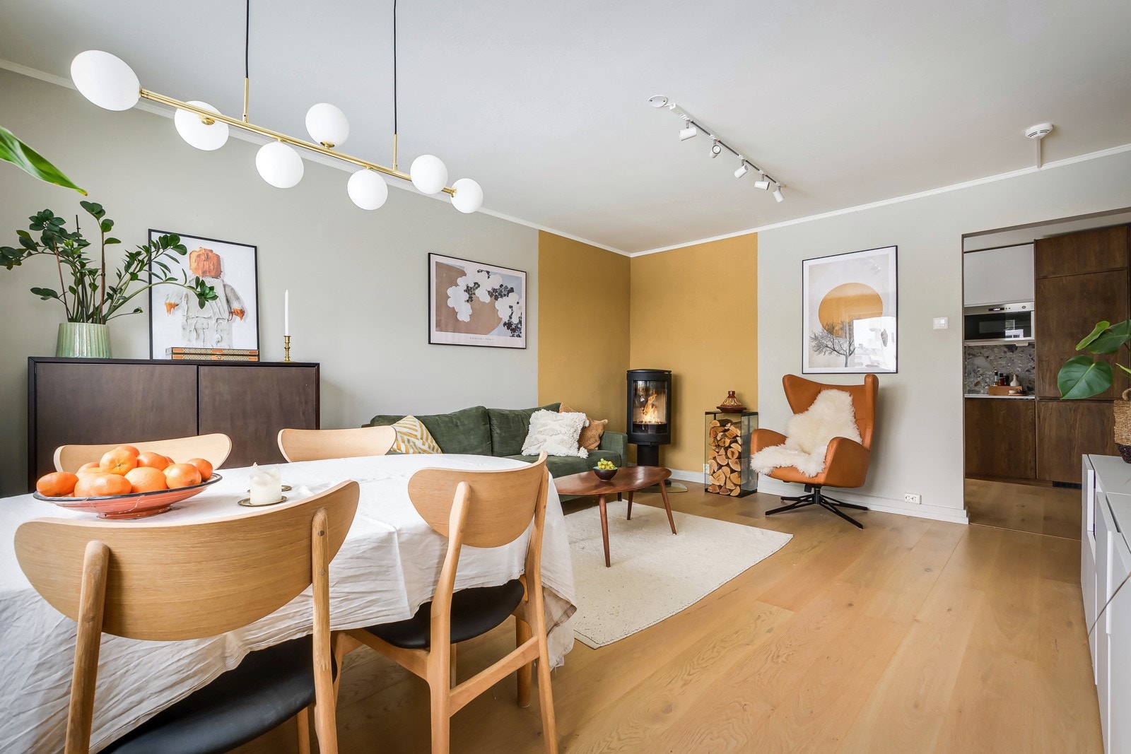 God standard med pen enstavs parkett på gulv og glatte overflater malt i en tidløs lys farge i kombinasjon med lekker kontrastvegg på begge sider av peisovnen. Galleribilde