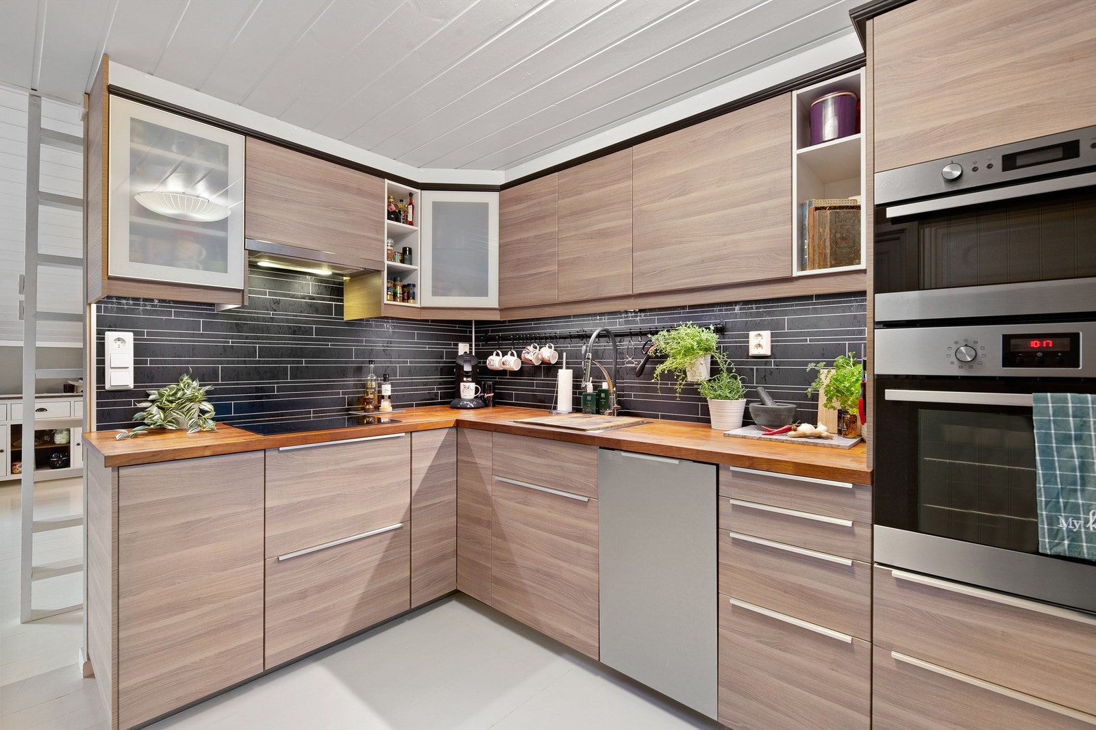 Laminerte plater på vegg over benkeplater av laminat og lysarmaturer under overskap Galleribilde