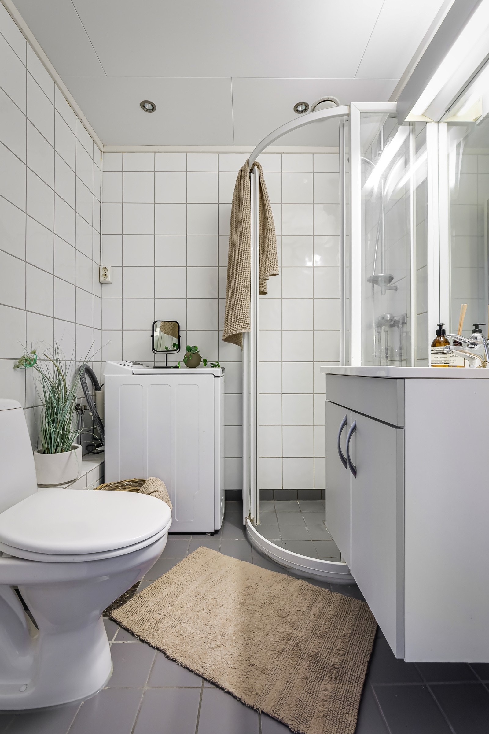 Baderommet er utstyrt med servantskap, veggspeil med belysning, dusjhjørne med glassdører og gulvstående toalett. Galleribilde