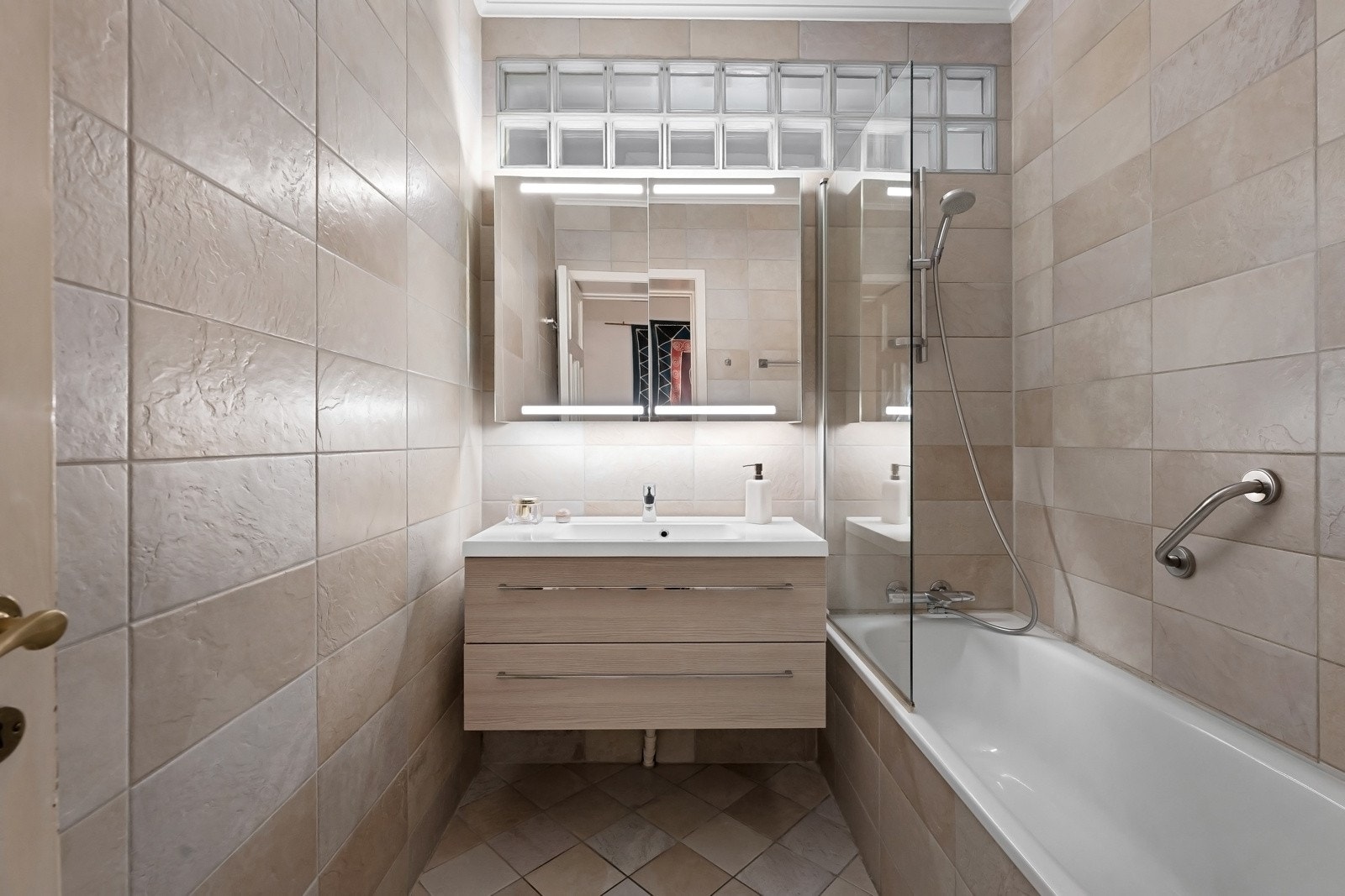 Badet ble oppgradert i 2011 og fremstår som tidløst og funksjonelt. Badet er utstyrt med servant med oppbevaringsskuffer, speilskap med integrert belysning, badekar og en delvis skjermet glassvegg. Varmkabler og mekanisk avtrekk Galleribilde