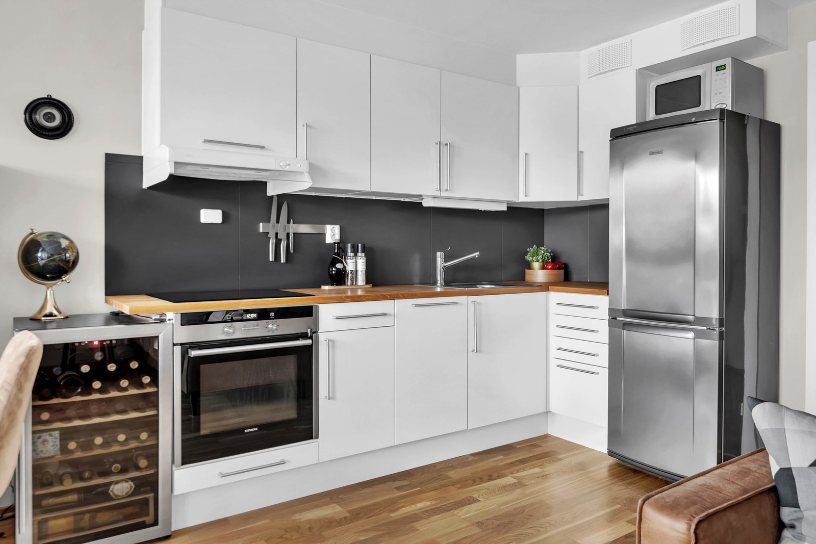 Praktisk kjøkkenløsning bestående av slette fronter, benkeplate av tre, kjøleskap med fryser og integrert oppvaskmaskin, stekeovn og induksjonstopp. Galleribilde