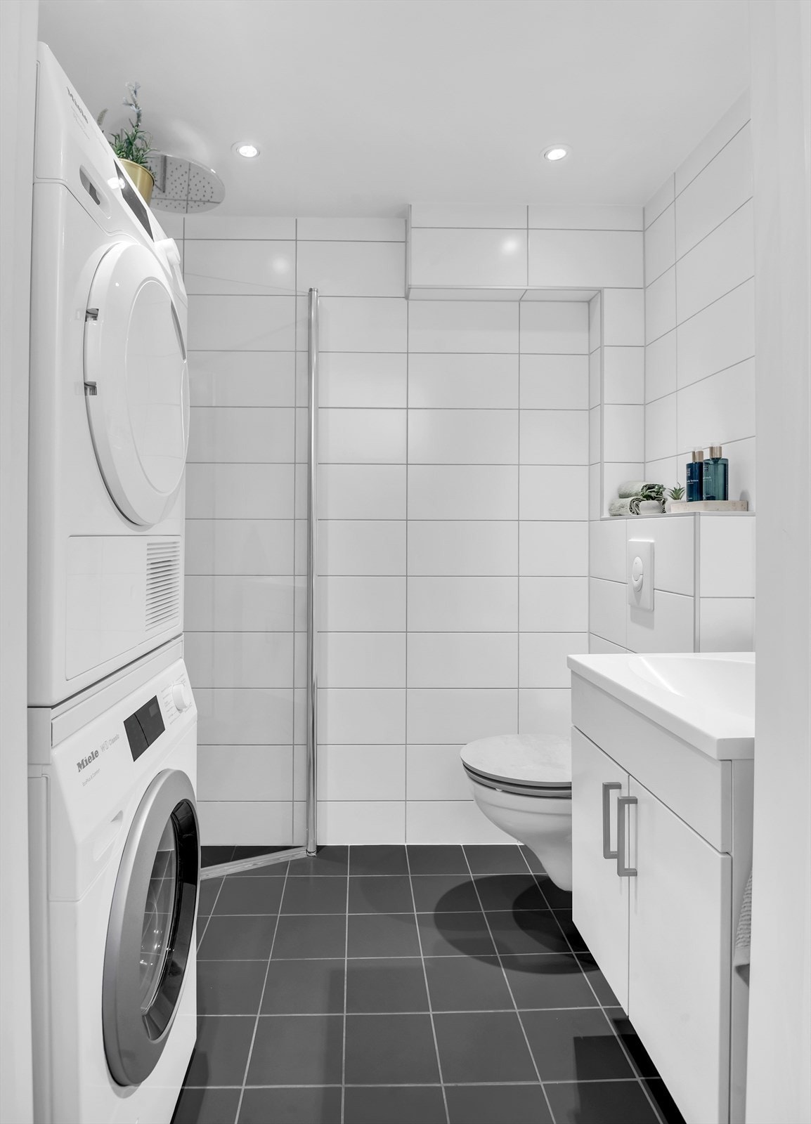 Badet har flislagt gulv med varme og flislagte vegger, nedsenket himling med downlights, vegghengt servantskap, innfelt speil og stikkontakt på vegg over servant. Galleribilde