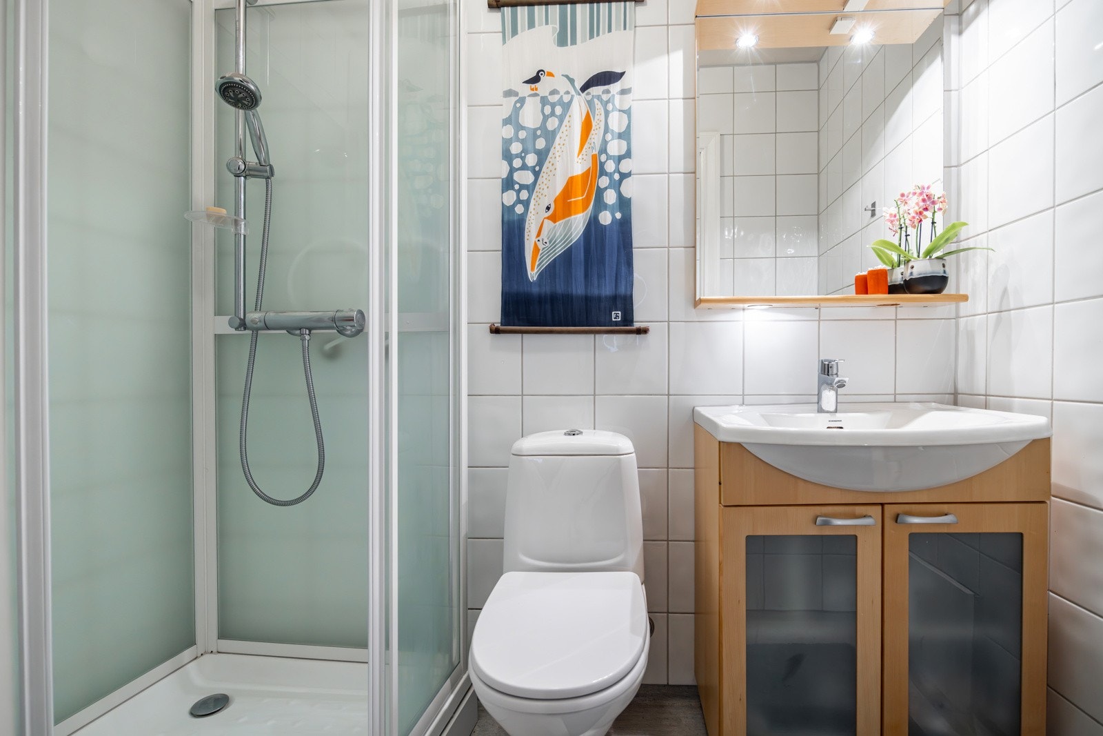 Bad med alle nødvendigheter. Badet har dusjkabinett, servantskap, toalett og vegghengt speil. Galleribilde