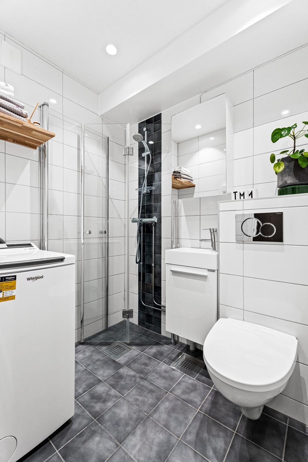 Delikat flislagt baderom med gulvvarme fra 2018. Badet har dusjhjørne med dører i herdet glass, veggfestet klosett, servant og opplegg for vaskemaskin. Galleribilde