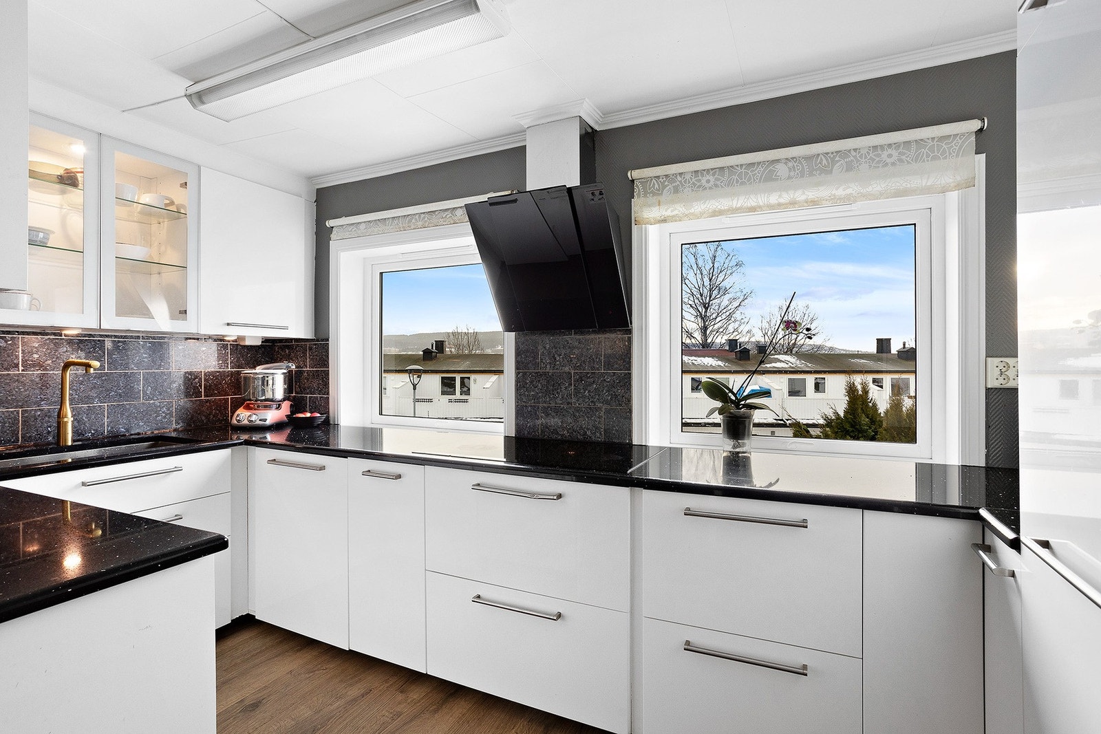 Et stilrent IKEA-kjøkken fra 2013 med glatte, hvite fronter og en elegant benkeplate i stein. Galleribilde