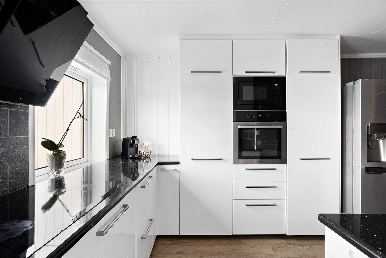 På kjøkkenet finner du både integrerte hvitevarer som oppvaskmaskin, induksjonstopp, stekeovn og mikrobølgeovn, samt plass til et frittstående side-by-side kjøl-/fryseskap. Galleribilde