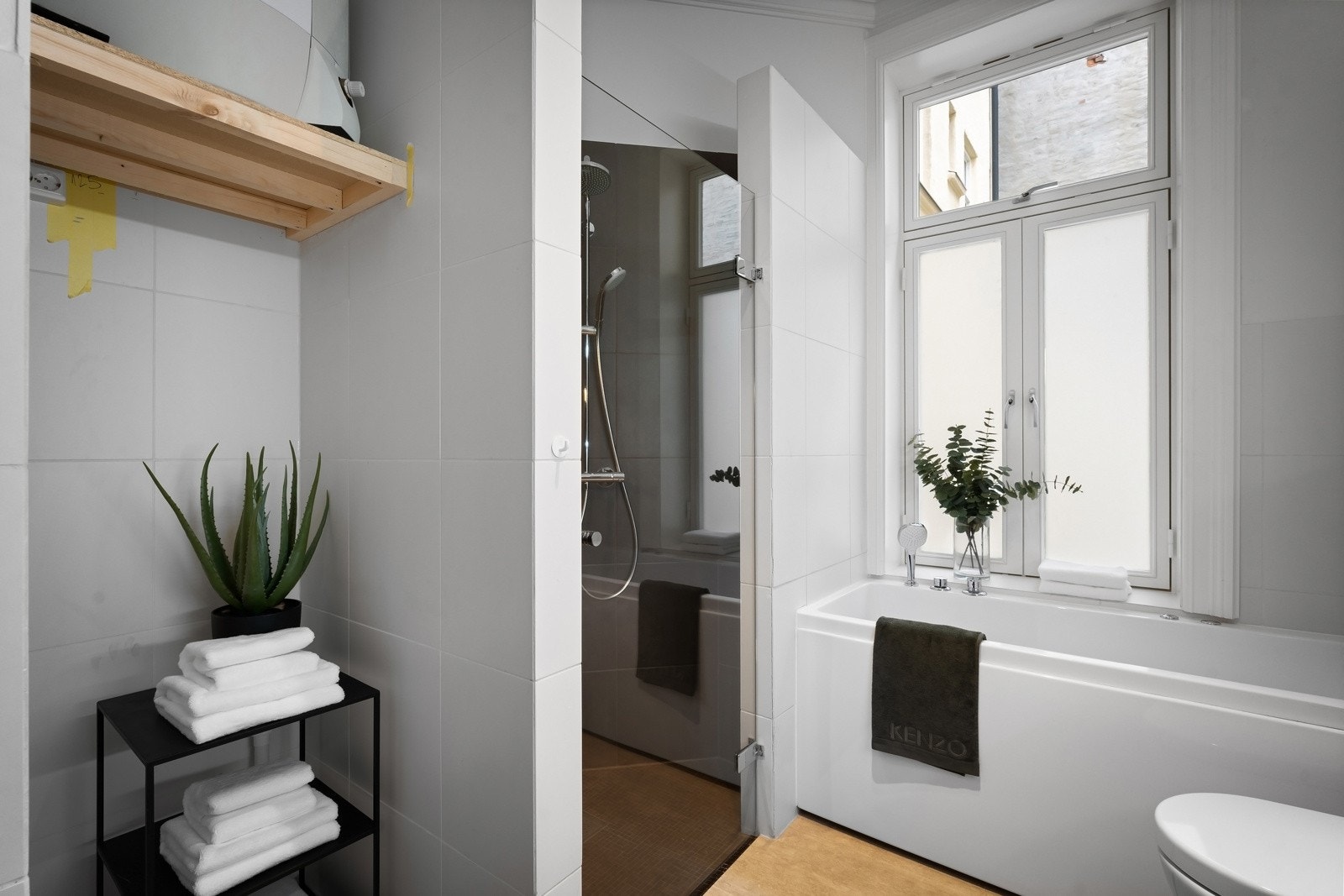 Badet har badekar, dusjsone med mosaikkfliser på gulvet, regnfallsdusj og glassdør Galleribilde