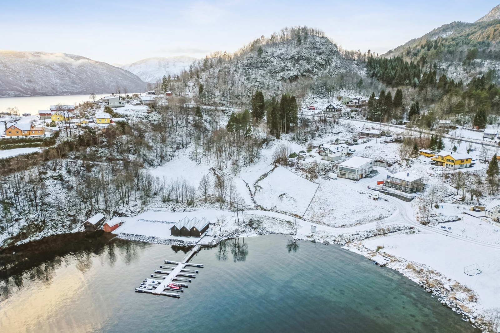 En skjermet og lun vik med bryggeanlegg, naust og bolighus. Galleribilde