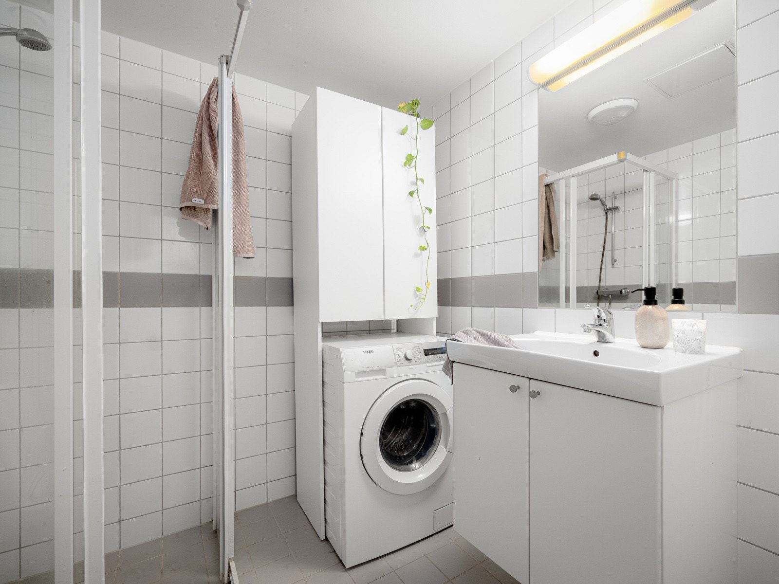 Pent og tidløst baderom med fliser på vegger og gulv. Det er gulvvarme på bad, samt plass og opplegg for vaskemaskin. Galleribilde