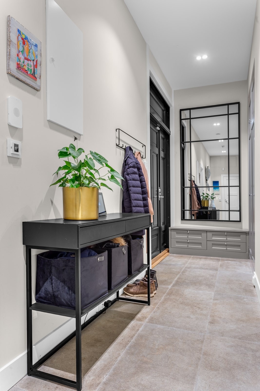 Romslig flislagt entré/gang med gulvvarme og downlights. Snekkerbygde garderobeskap Galleribilde