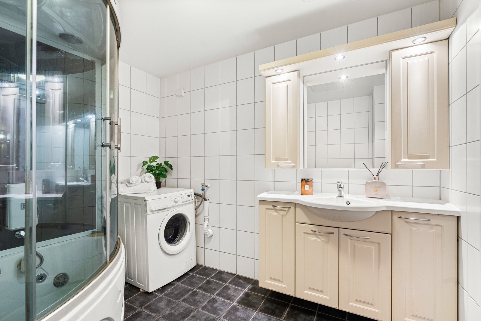 Badet er utstyrt med dusjkabinett med skyvedører, dusjarmatur tilkoblet hånddusj og massasjedusj, og opplegg for vaskemaskin. Galleribilde