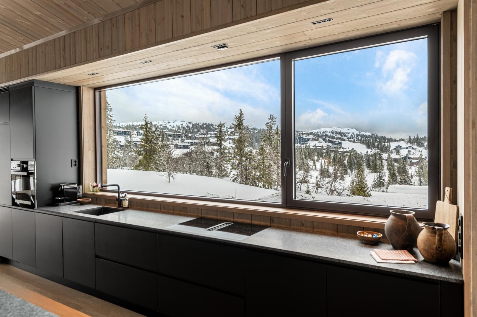 Kjøkken i åpen løsning med skreddersydd innredning, integrerte hvitevarer og et generøst kjøkkenvindu i langfasaden. Galleribilde